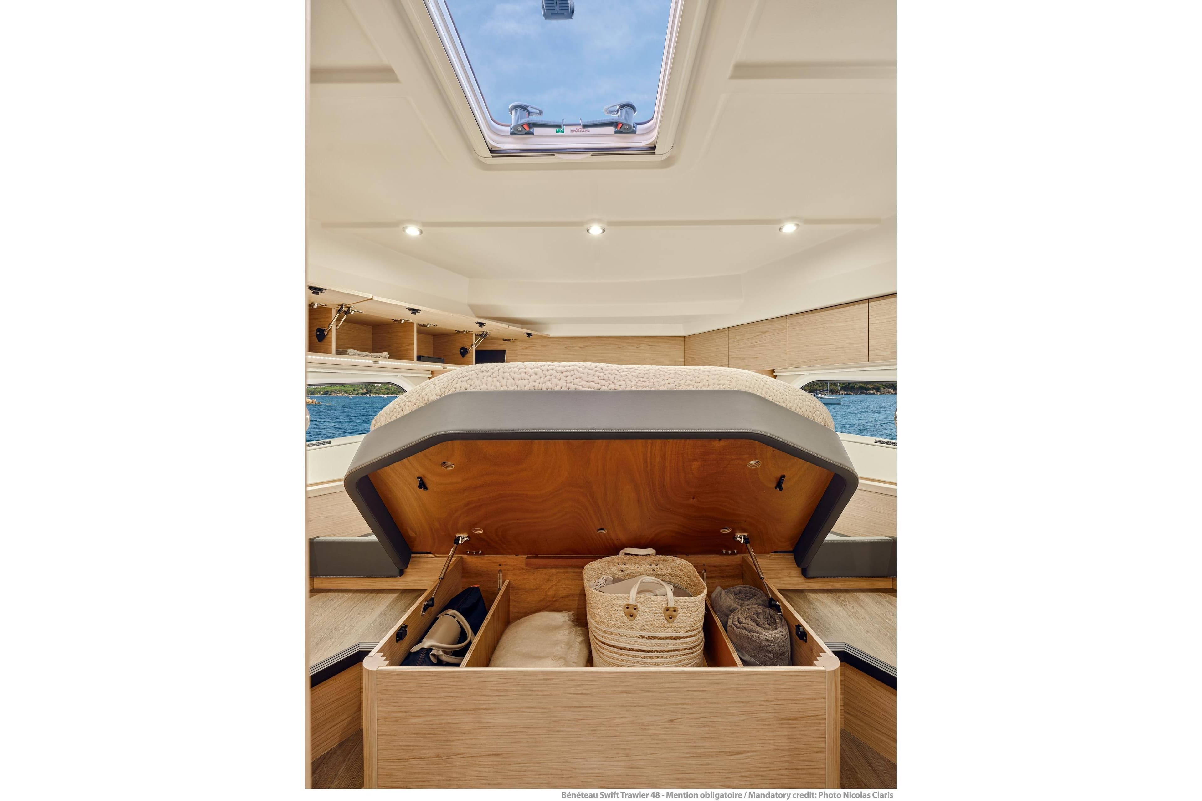 Interior of 2026 Beneteau Swift Trawler 48 with under-bed storage and skylight view.