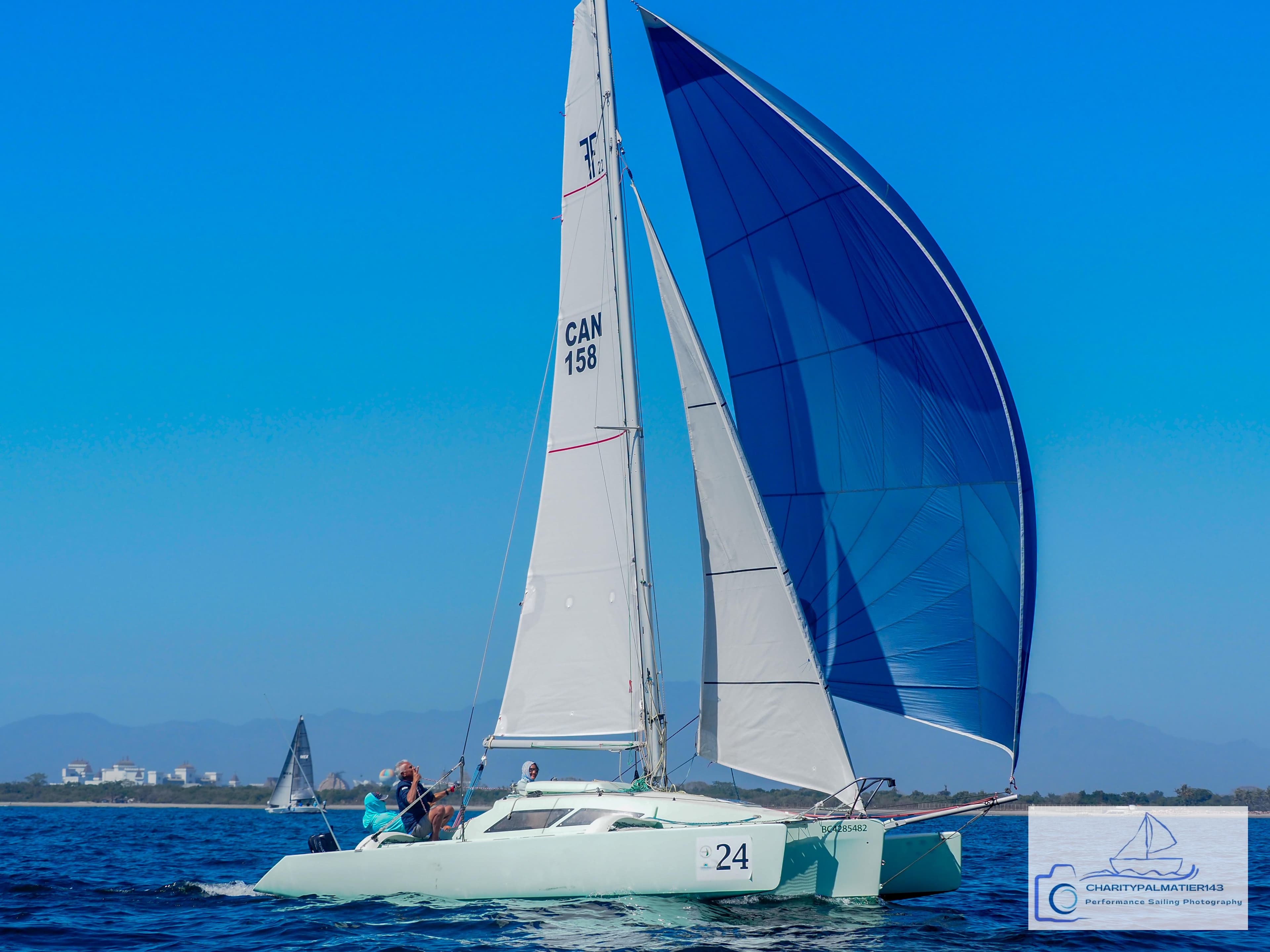 Sailboat "Melvest Marine F-22" gliding on blue water, vibrant sails, clear sky, 2011 model.