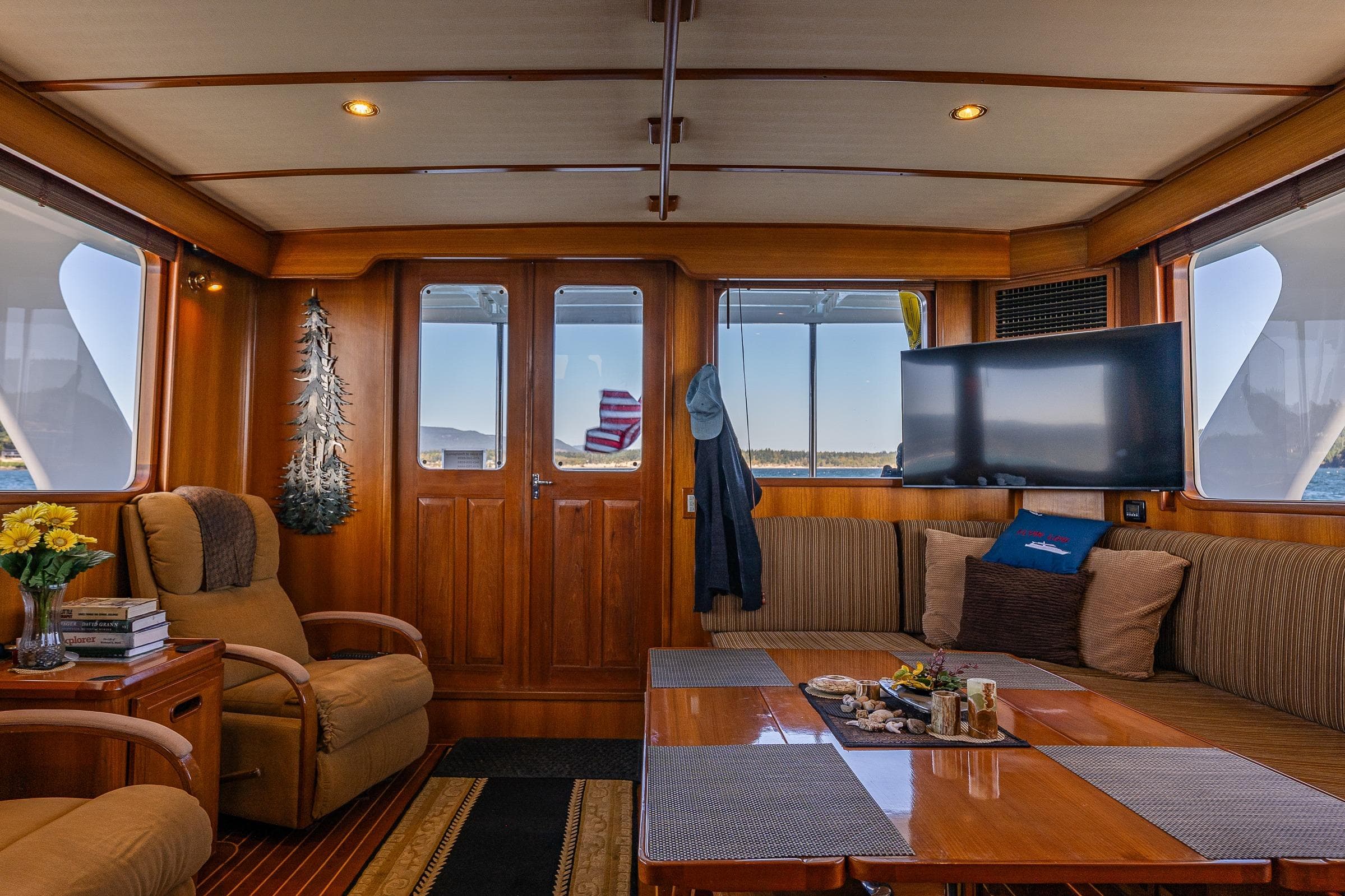 Luxurious 2007 DeFever 56 yacht interior with cozy seating, wooden decor, and large windows.