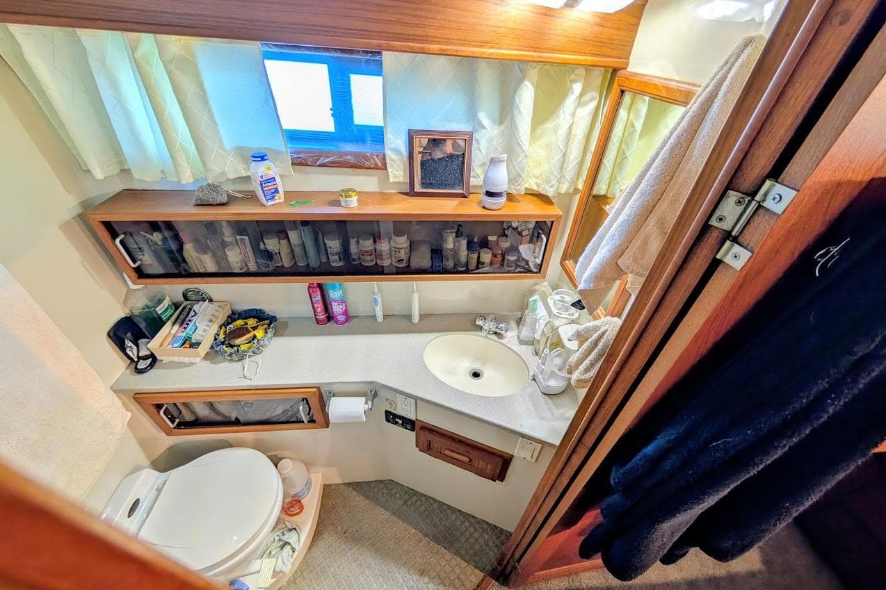 Bathroom interior of a 1990 Carver 55 yacht, featuring sink, toiletries, and storage.