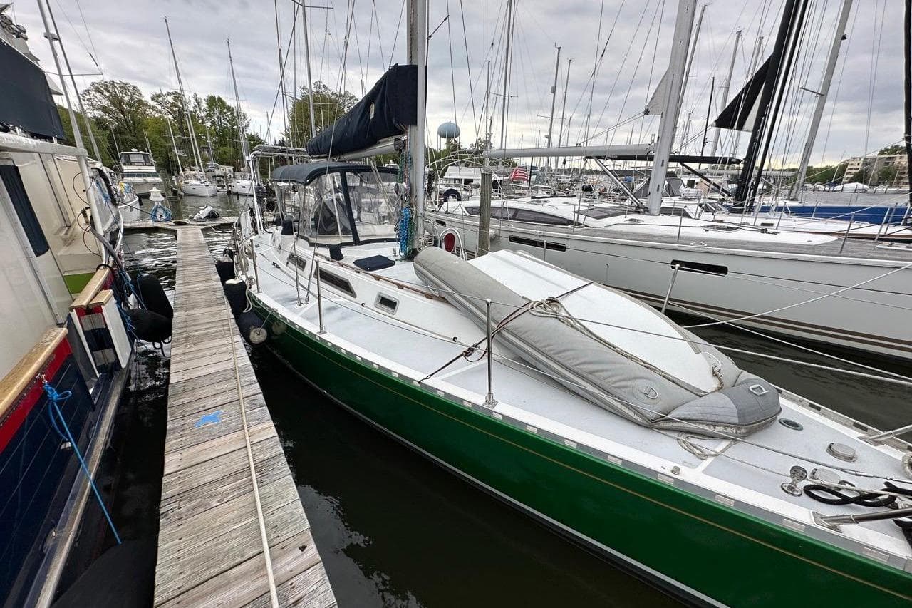 Sailboat docked in marina, 1989 Hylas 44 model, green hull, overcast sky.