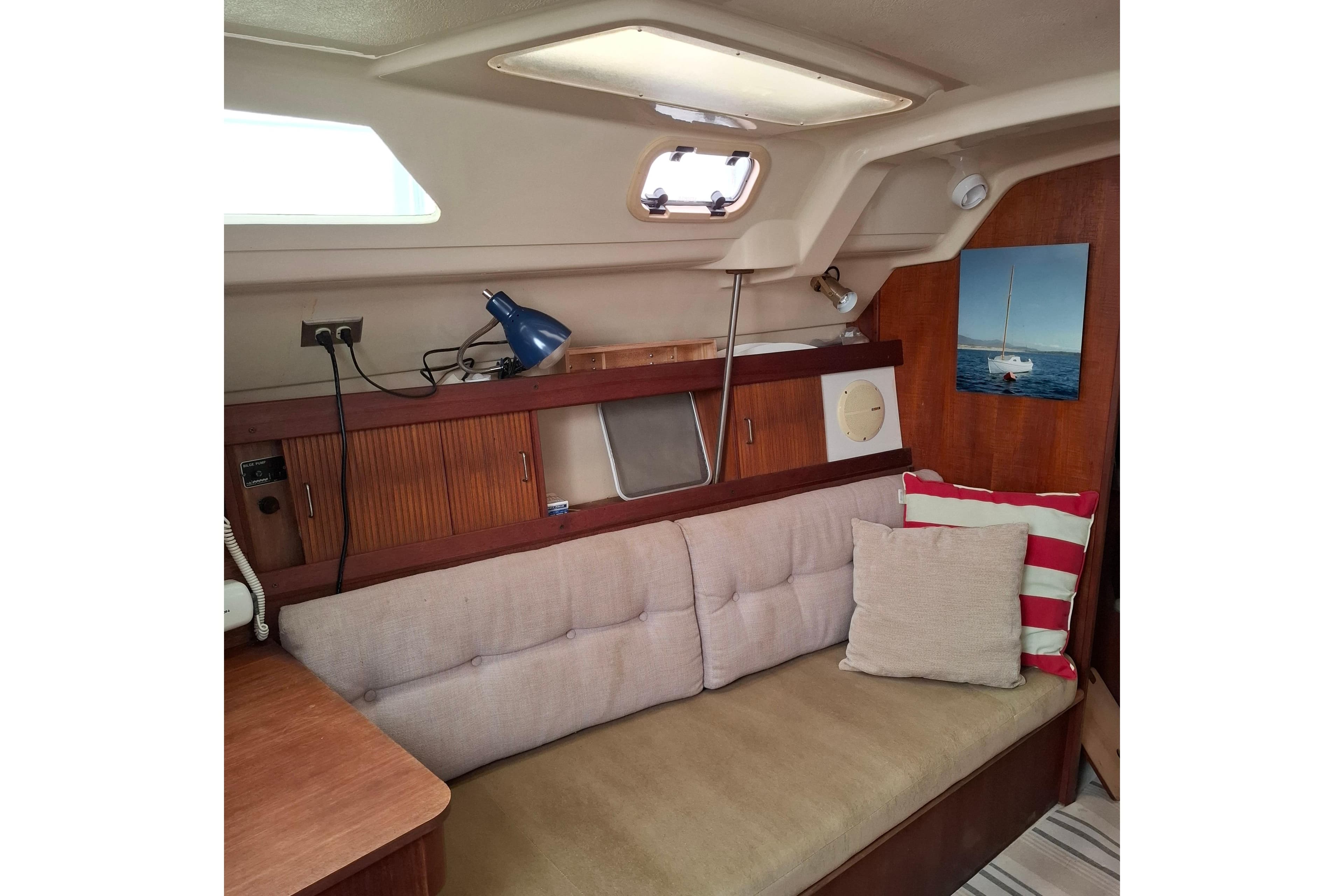Cozy interior of 1989 Hunter 30 sailboat with cushioned seating and nautical decor.