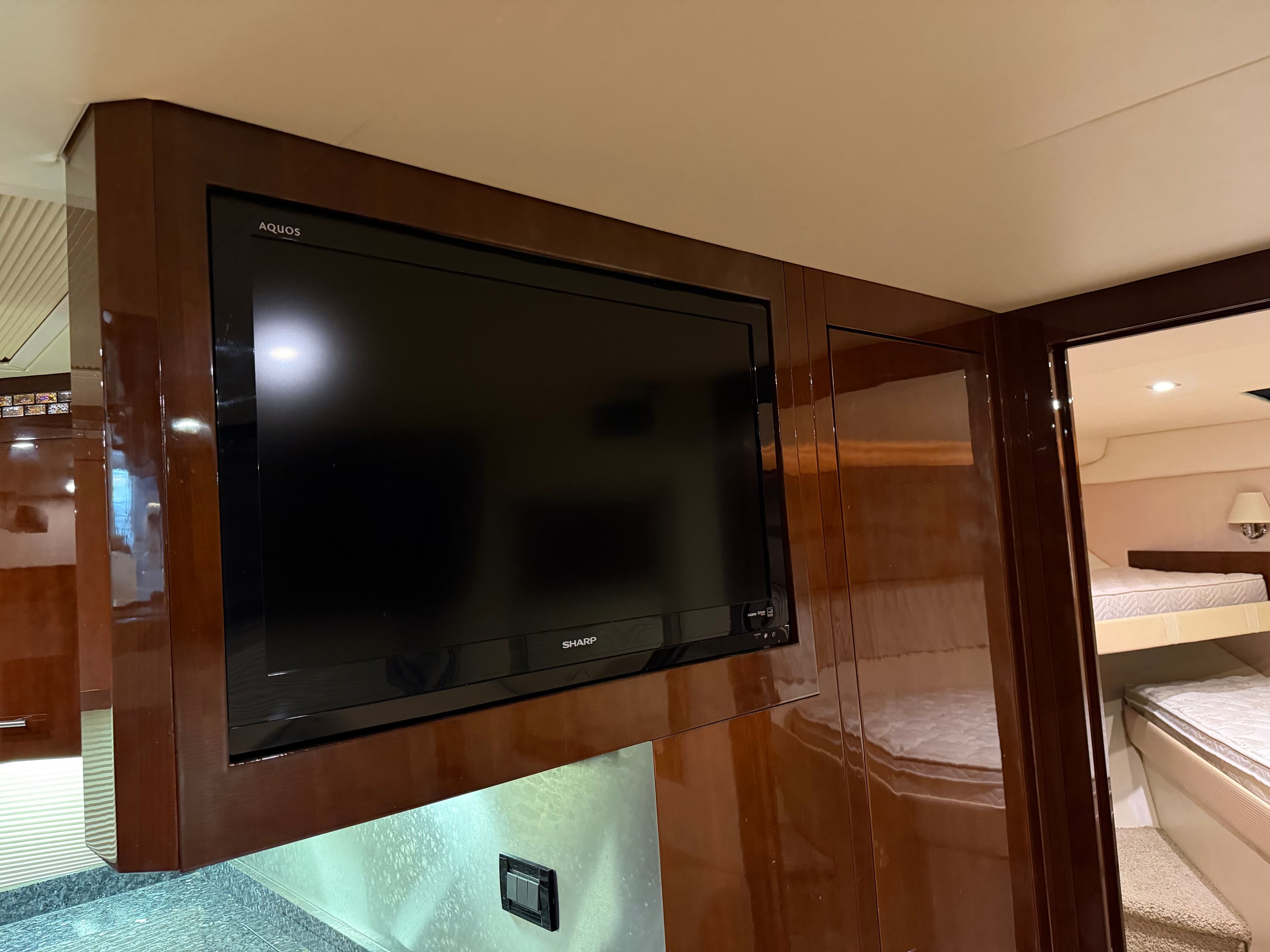 Flat-screen TV in 2014 Regal 52 Sport Coupe yacht interior, featuring wood paneling and cozy cabin.