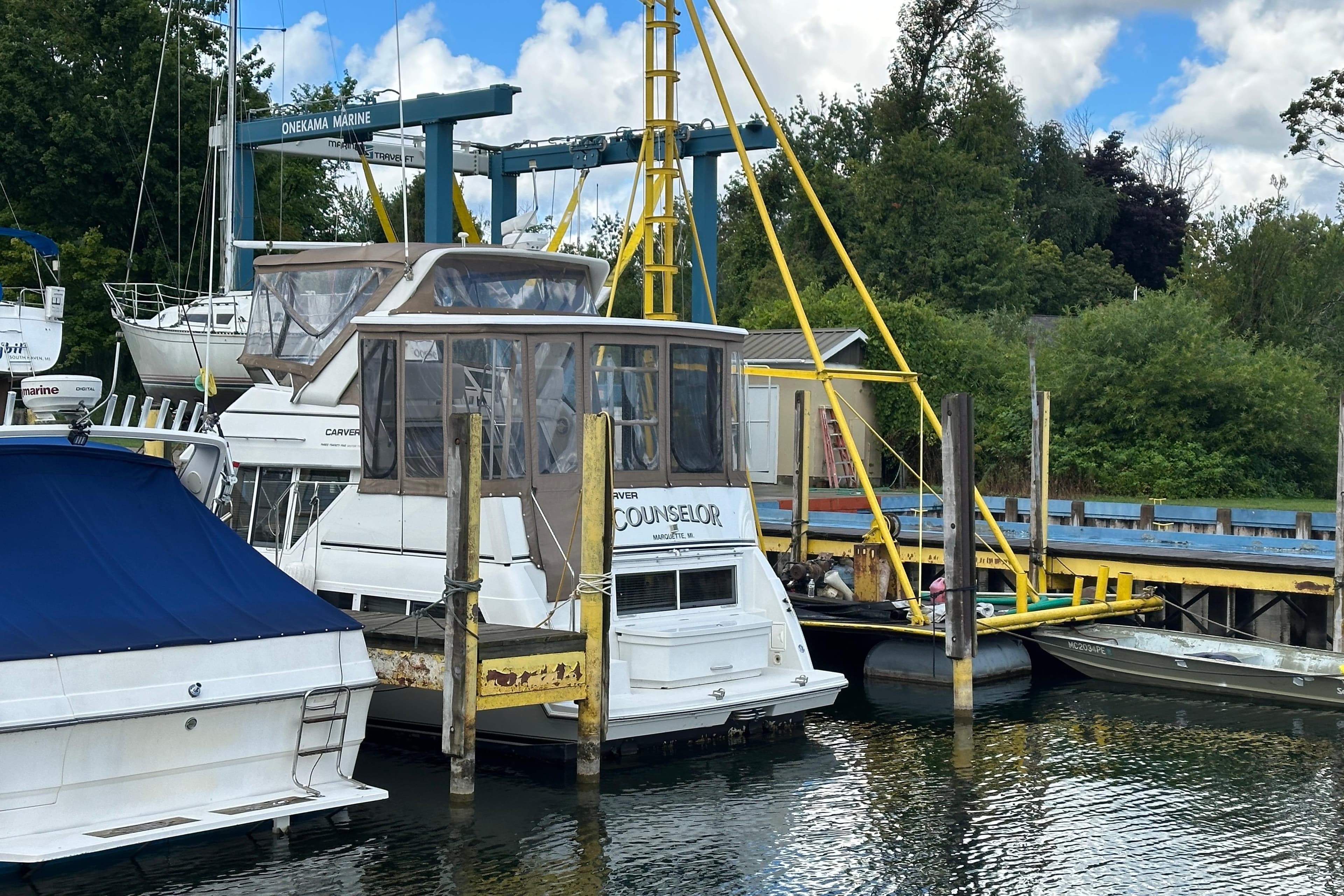 1997 Carver 325 Motor Yacht docked at Onekama Marine, surrounded by lush greenery.