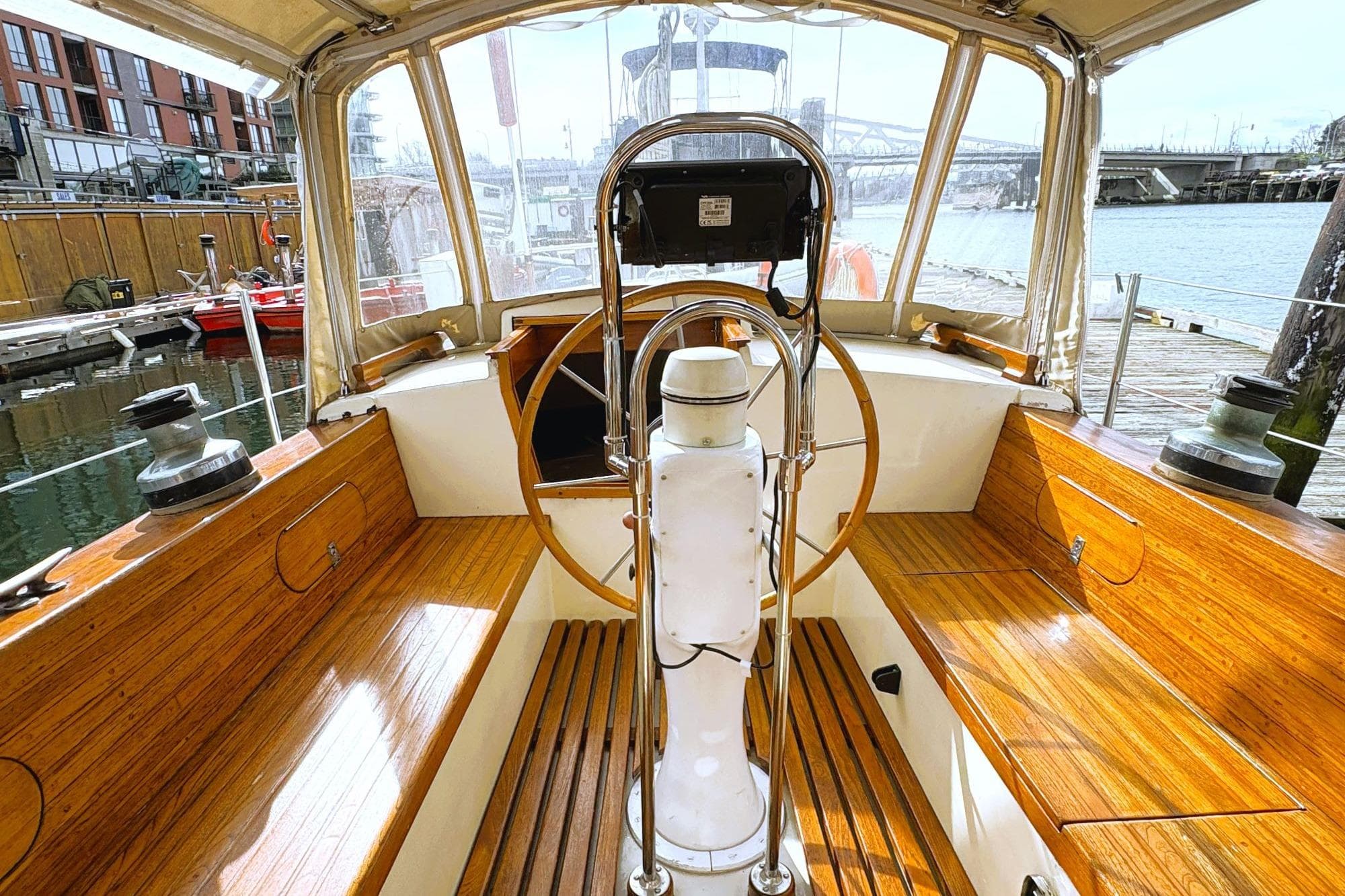Interior view of 1980 Discovery 42 sailboat cockpit with wooden seating and steering wheel.