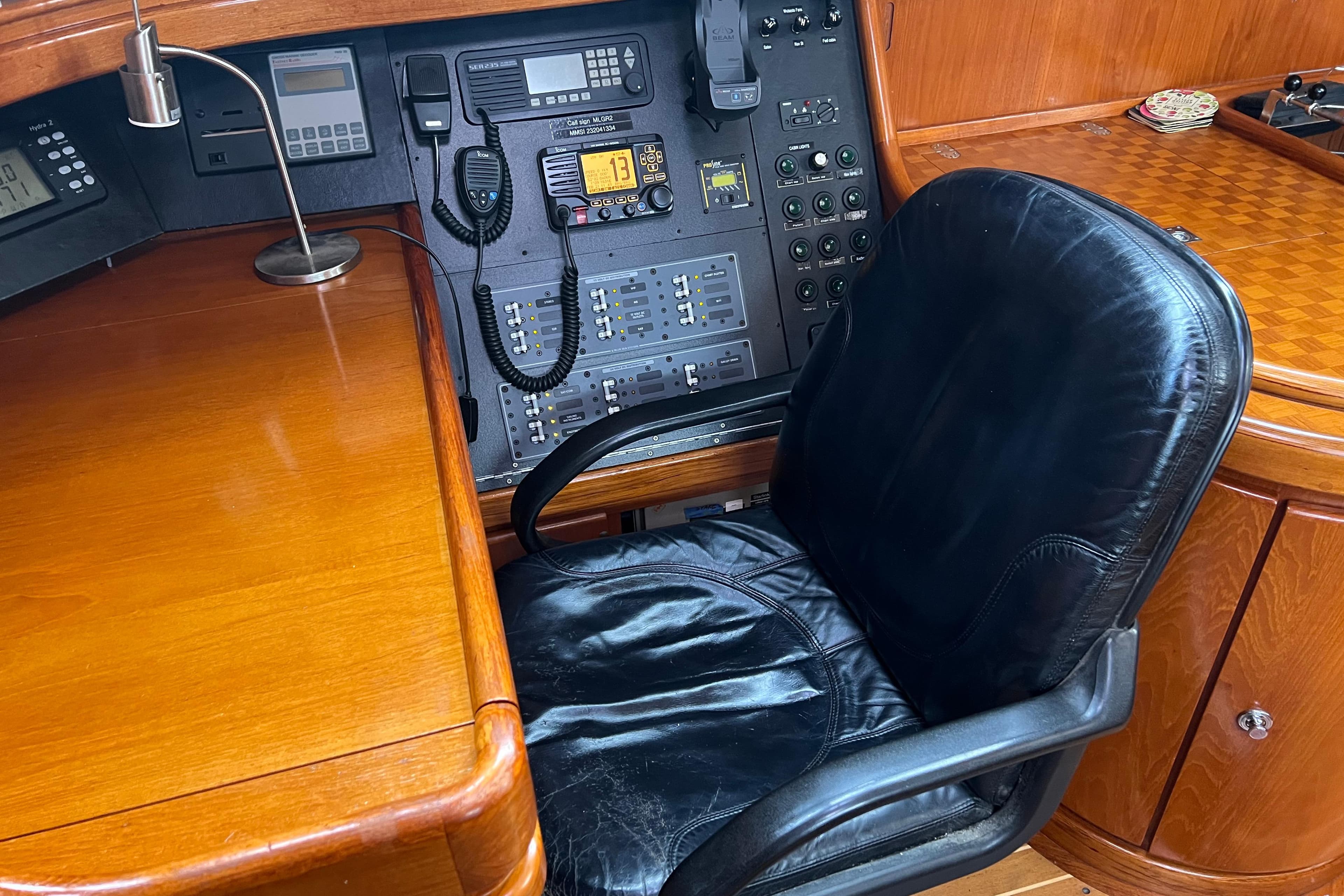 Navigation station of a 1990 Trintella 49A yacht with control panel and leather chair.