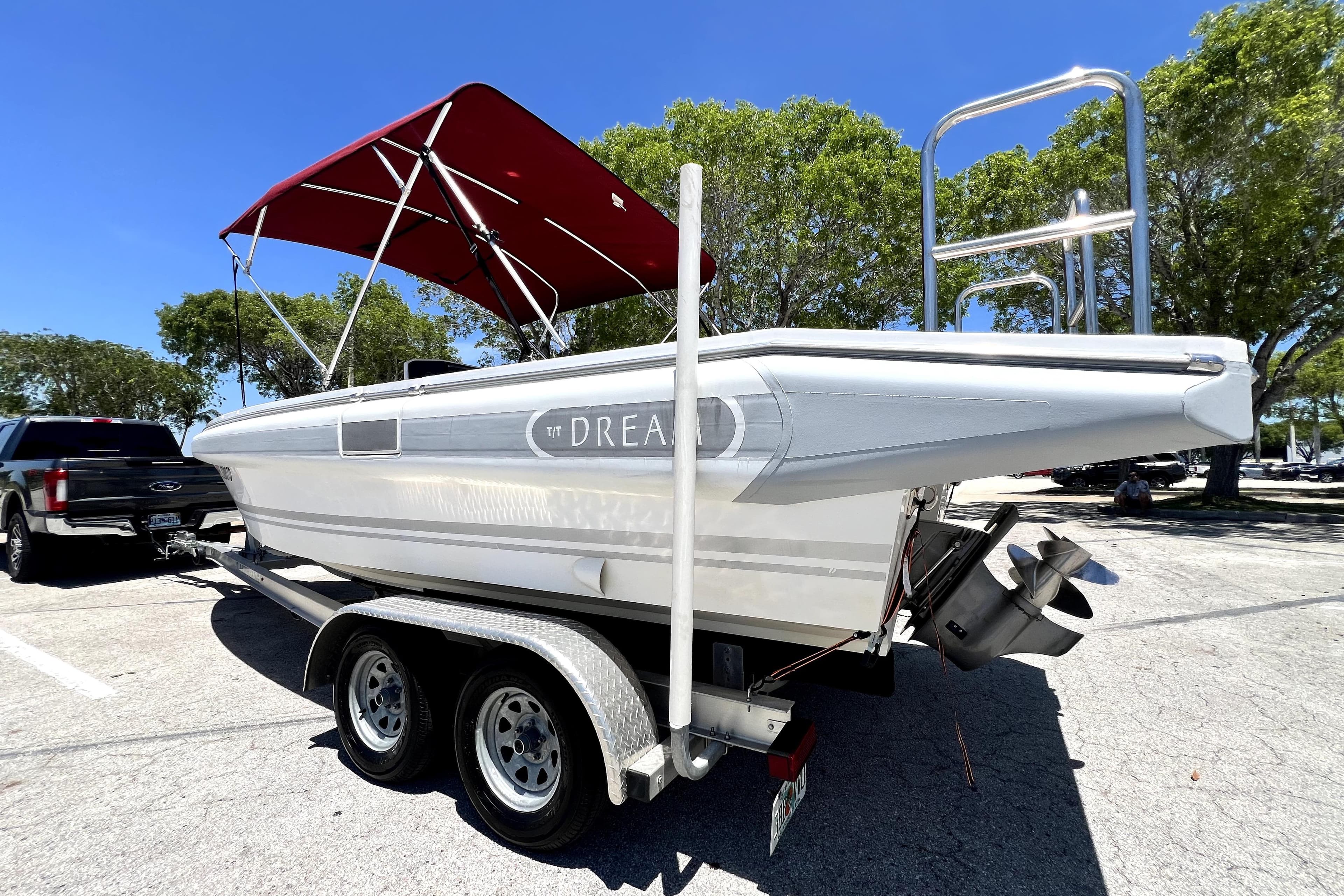 2013 Novurania Chase 23 boat on trailer with red canopy in parking lot.