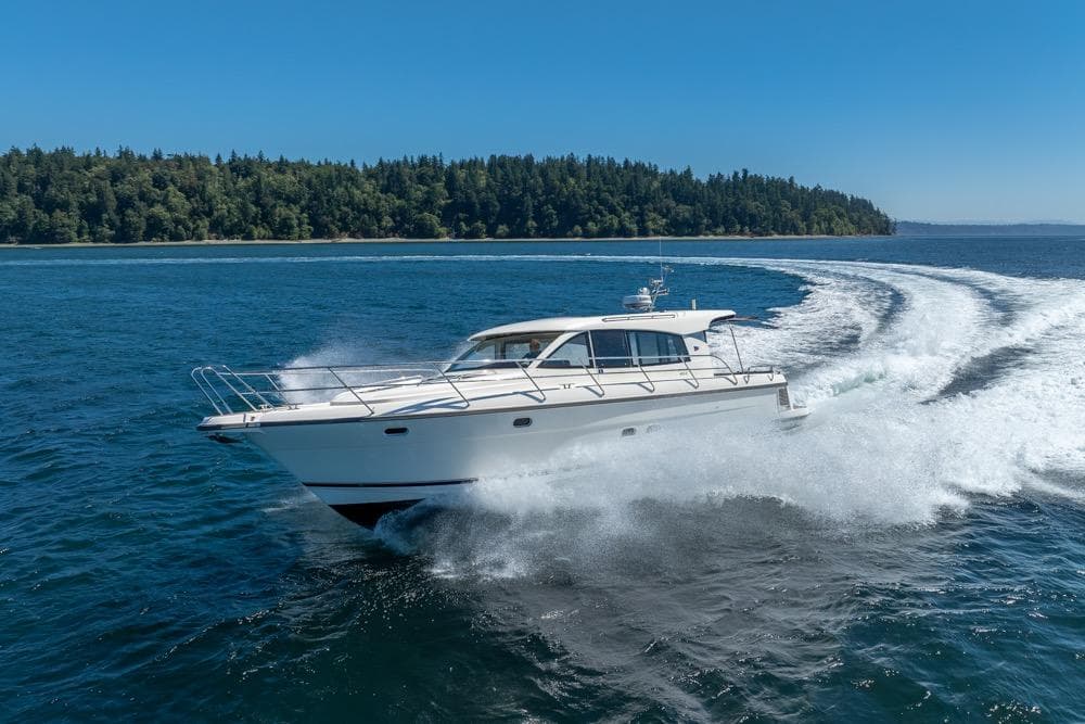 Nimbus 405 Coupé 2022 cruising on open water with forested shoreline in background.