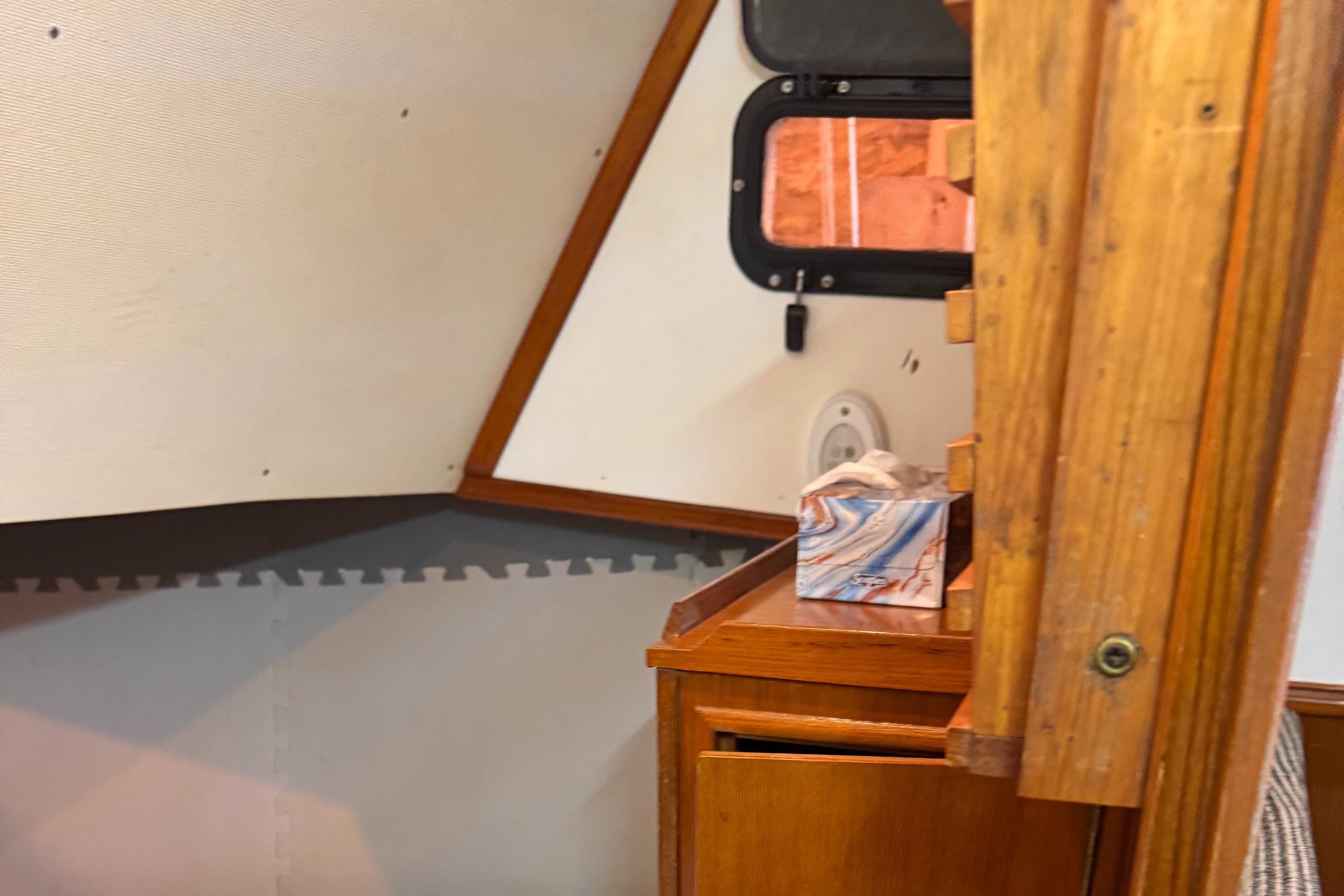 Interior of a 1979 Hyundai Roughwater 29 boat, featuring wooden cabinetry and a small window.