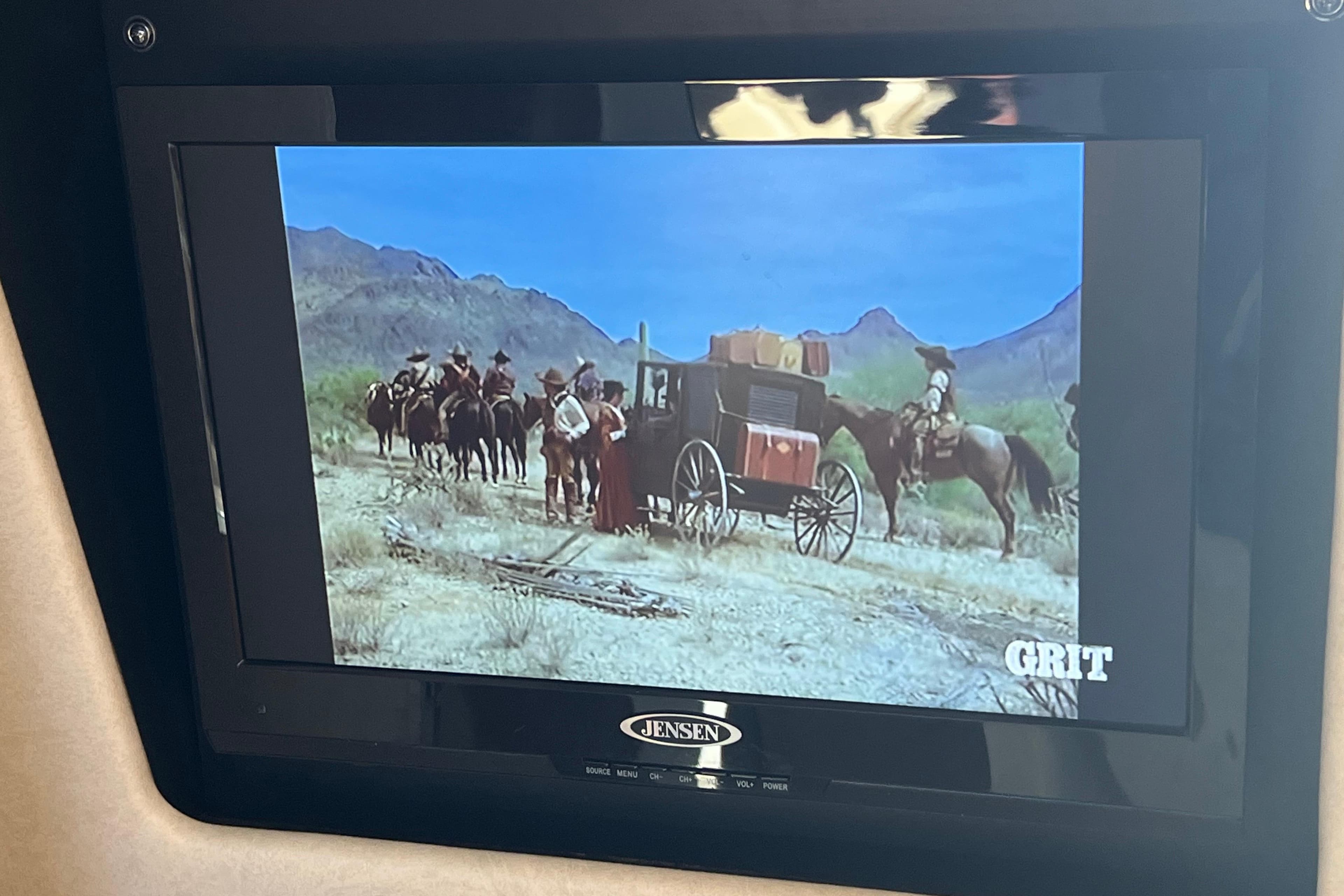 TV screen on a 2013 Sea Ray Sundancer 280 showing a Western scene with horses and a stagecoach.