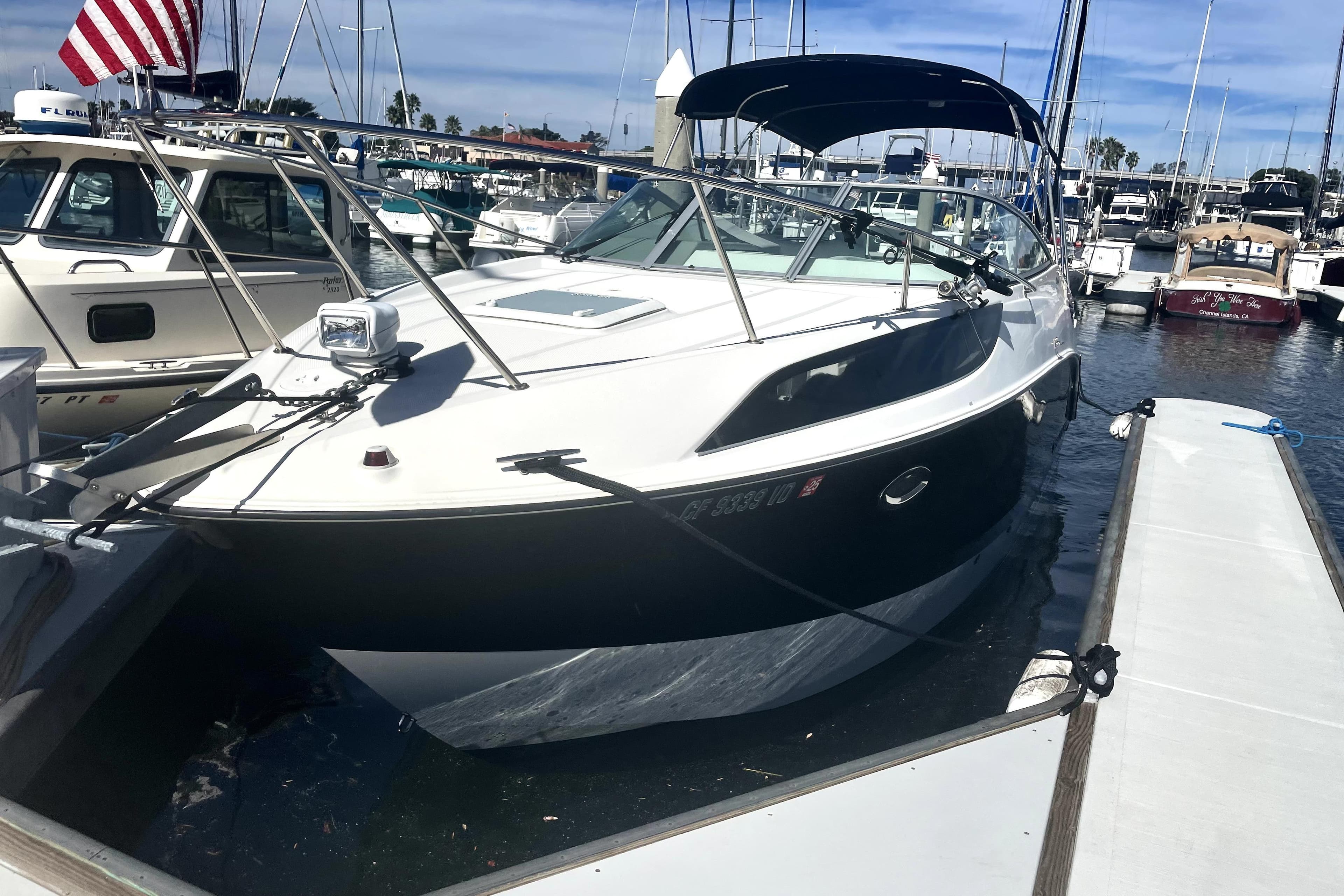 2010 Bayliner 255 Cruiser docked at marina under clear blue sky.