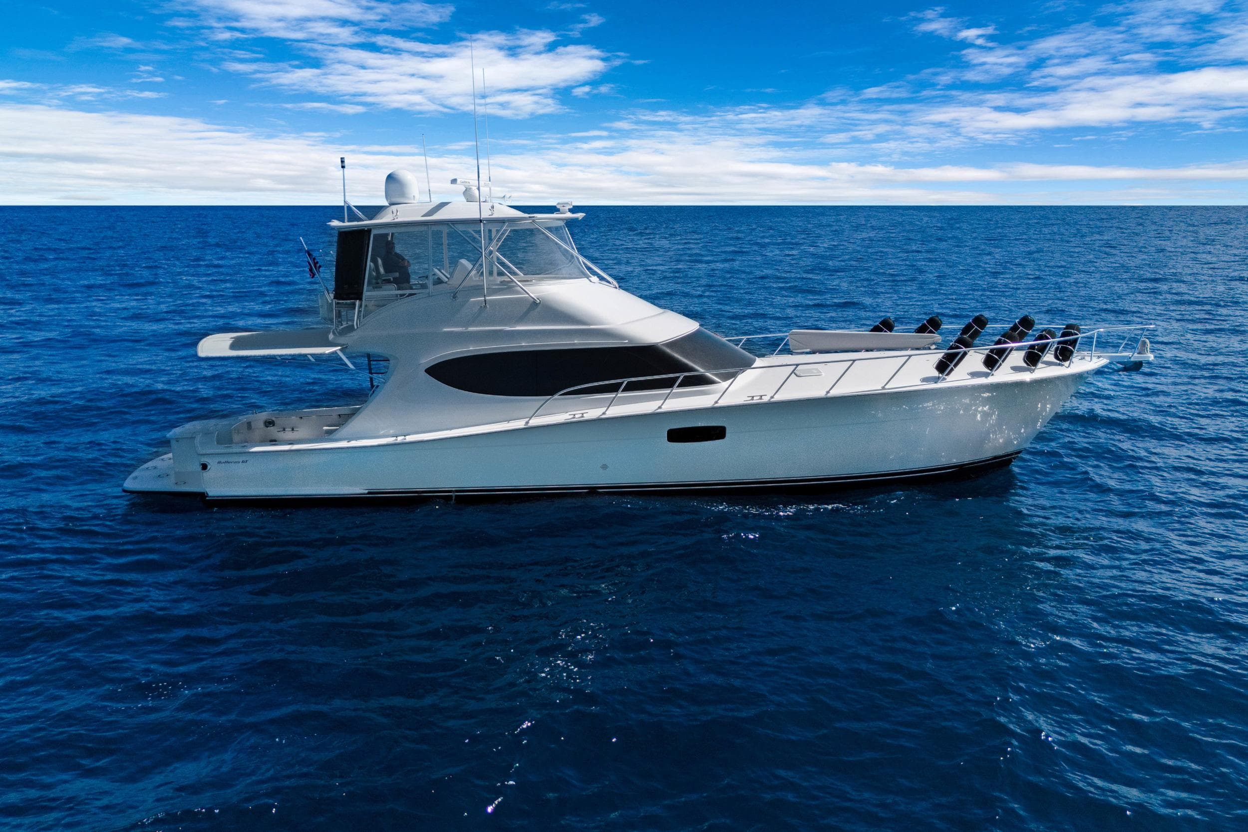 2016 Hatteras 63GT yacht cruising on open ocean under clear blue sky.