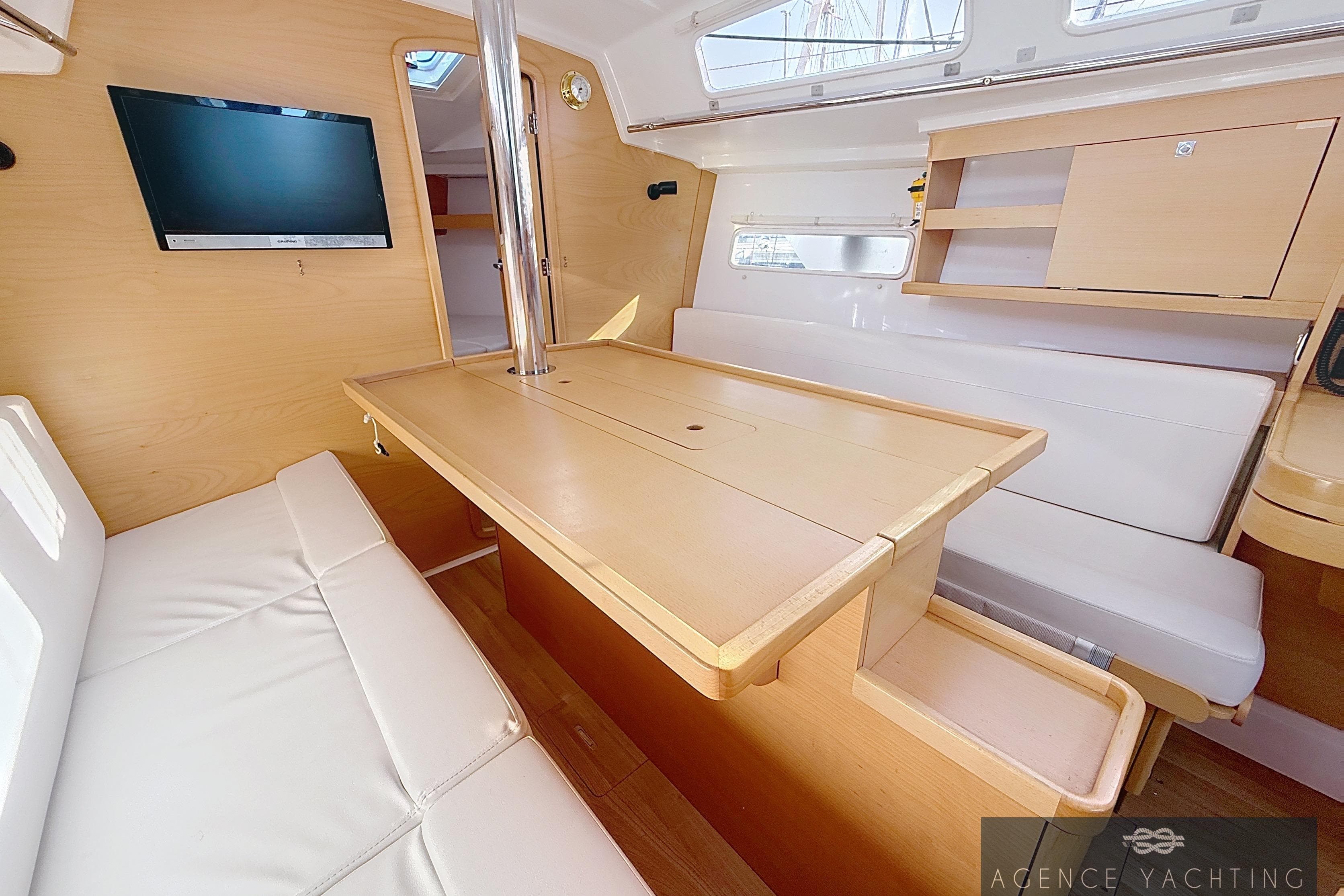2019 Jeanneau Sun Odyssey 319 interior with modern seating, table, and mounted TV.