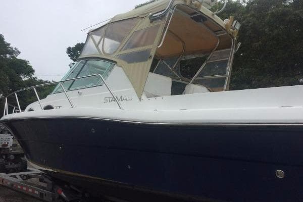 2000 Stamas 310 Express boat with a blue hull and beige canopy on a trailer.