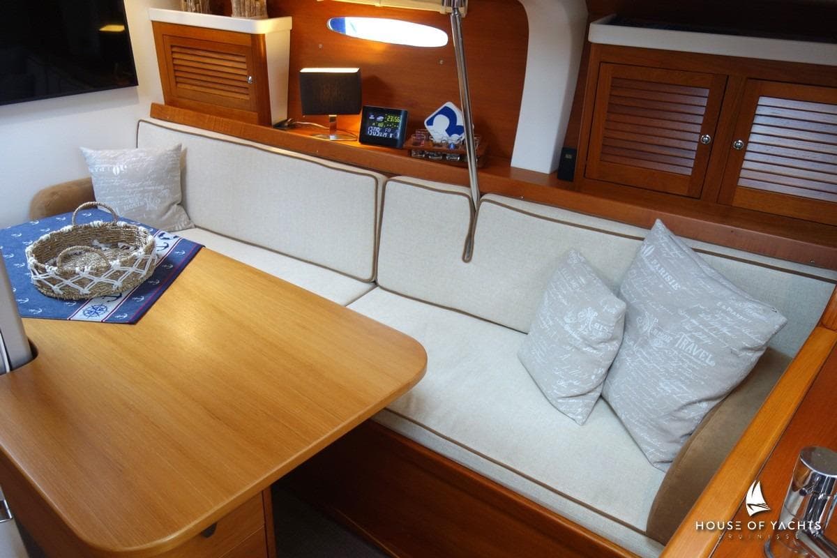 Cozy yacht interior with wooden table, cushioned seating, and decorative pillows, Von Ahlen 403, 2014.