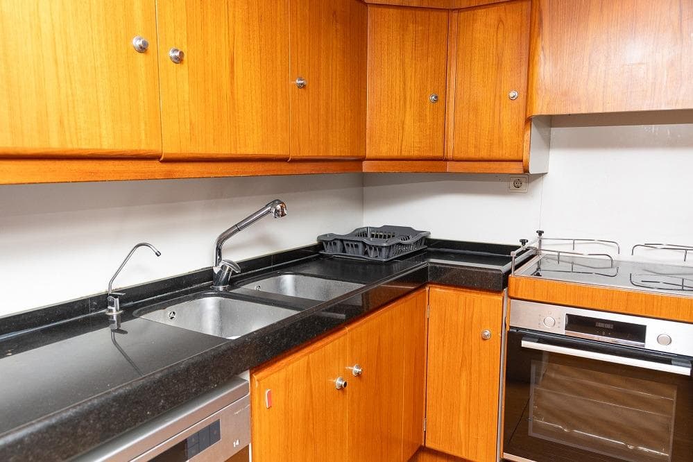 Wooden yacht kitchen with black countertops, dual sinks, and modern appliances. Jongert 30M, 1996.