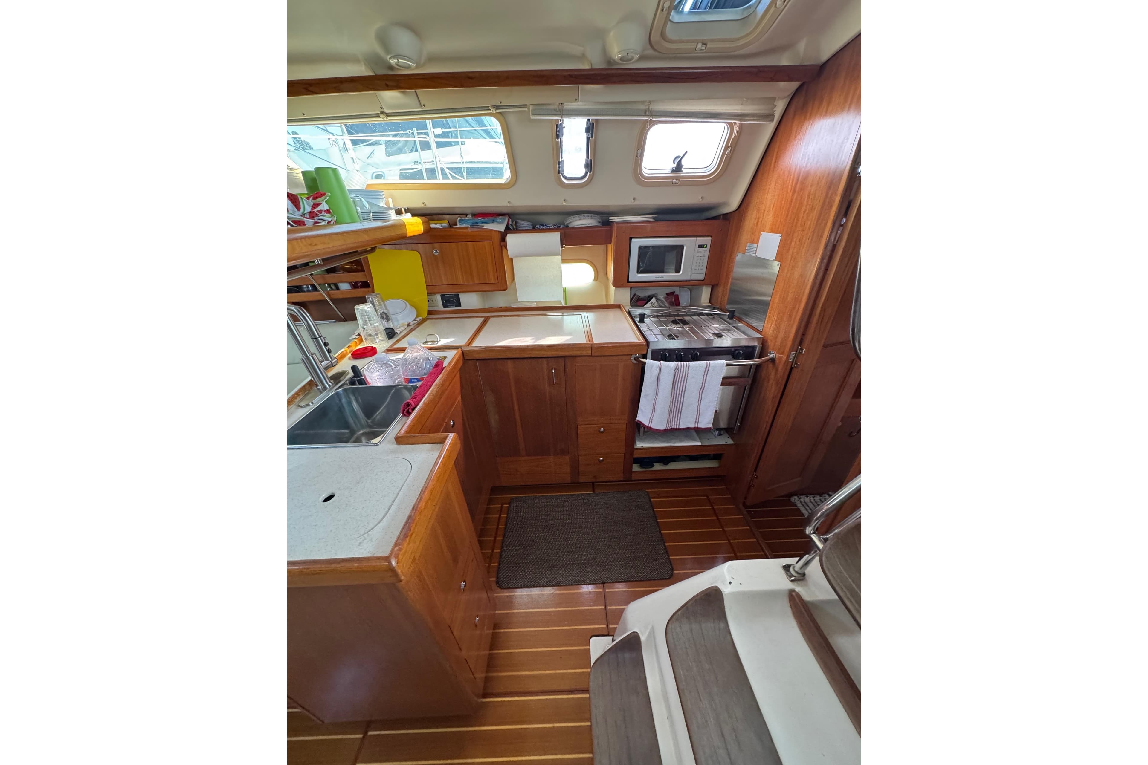 Interior of a 2002 Hunter 410 sailboat kitchen with wooden cabinetry and appliances.
