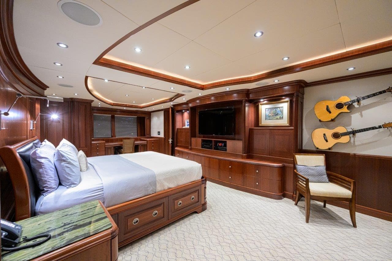 Luxurious 2011 C & G Boatworks Explorer bedroom with elegant wood finishes and mounted guitars.