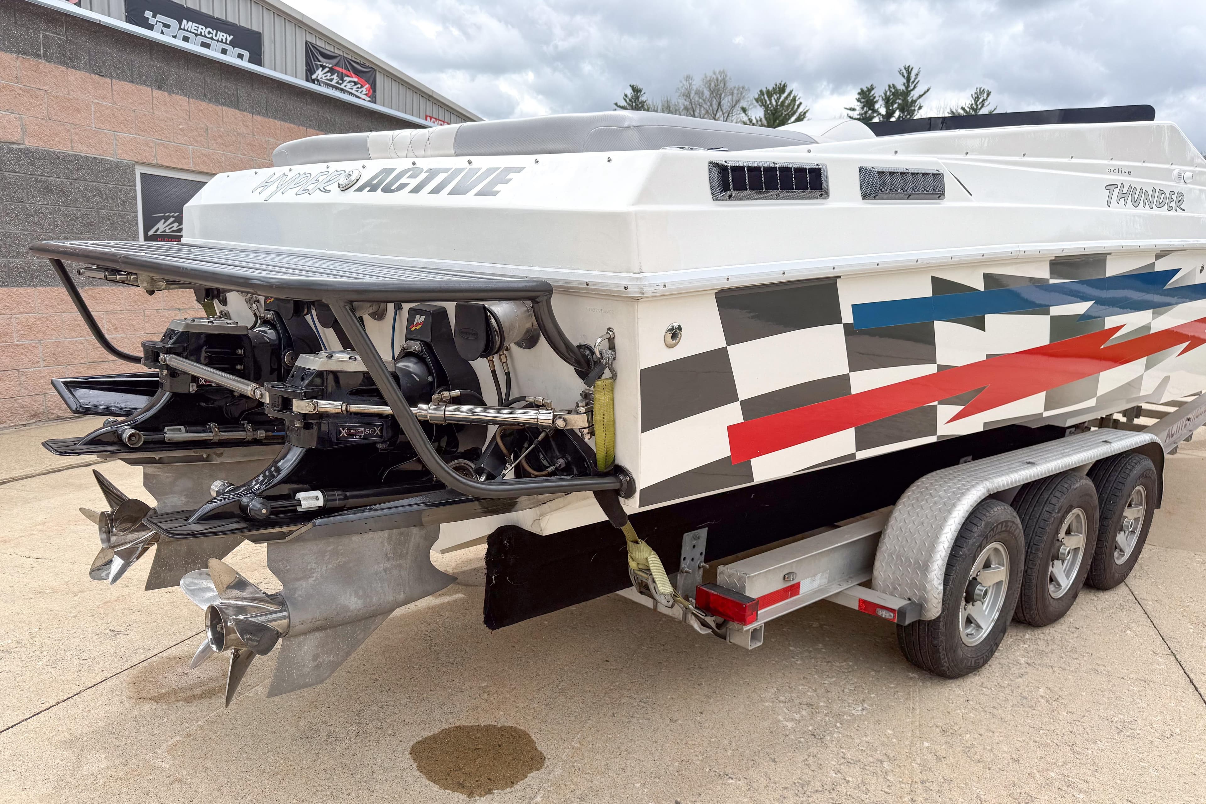2002 Active Thunder 37 boat on trailer, featuring vibrant geometric graphics and dual propellers.