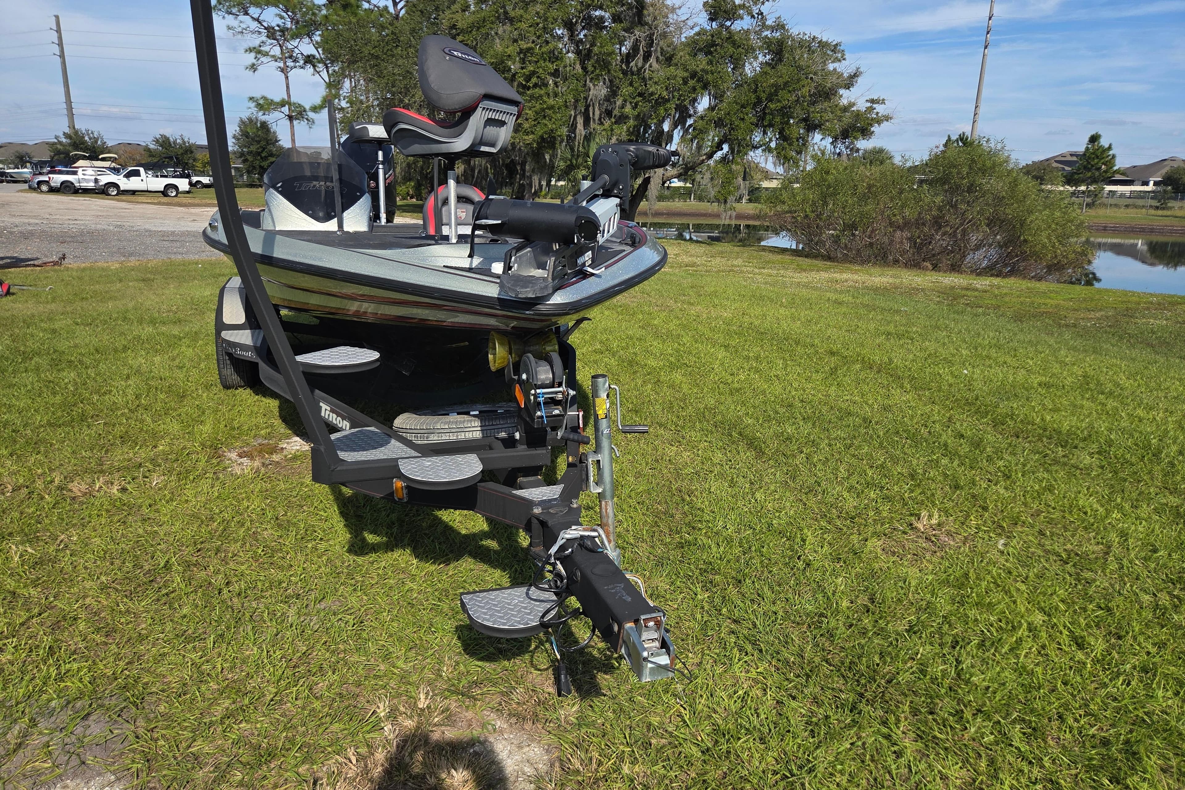 2021 Triton 20 TrX boat on trailer, parked on grassy area near water.