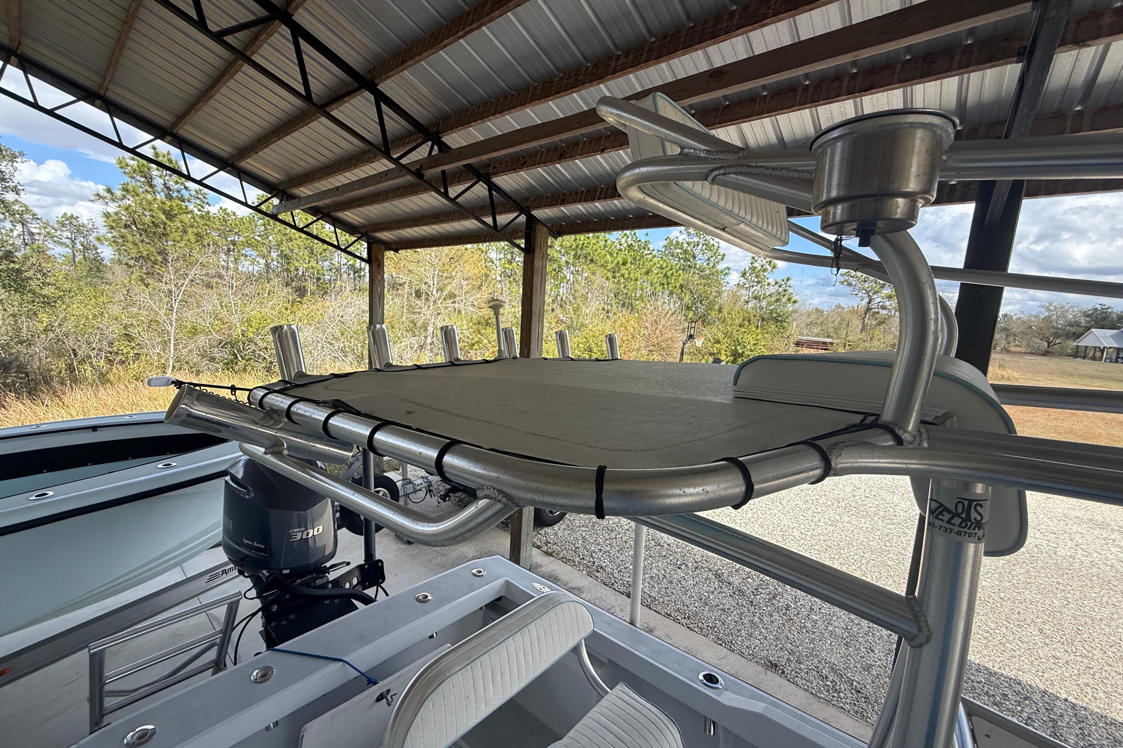 1974 Aquasport 2400 Center Console boat under a metal canopy, featuring a powerful outboard motor.