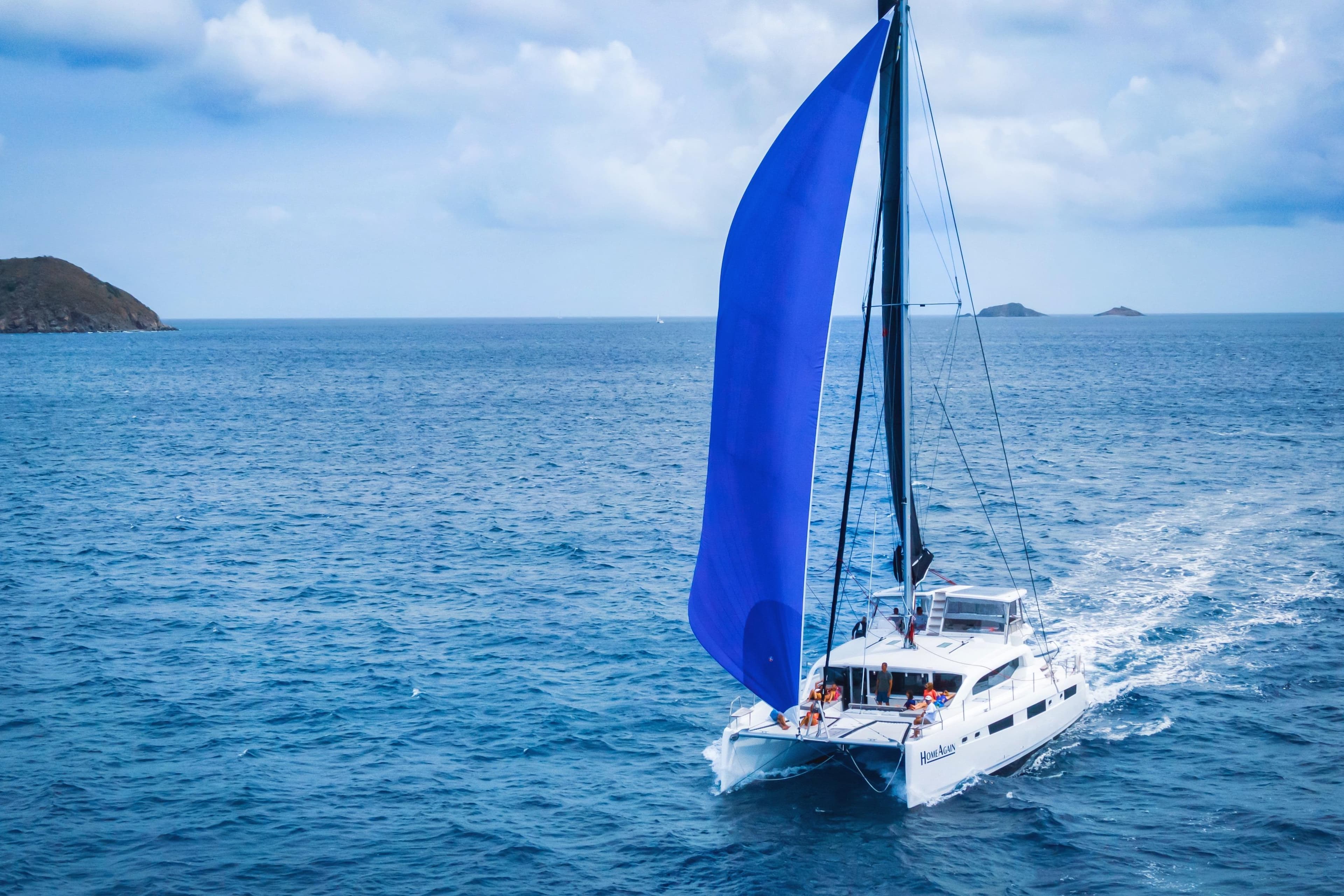 Sailing Voyage Yachts 590e catamaran with blue sail on open sea, 2021 model.