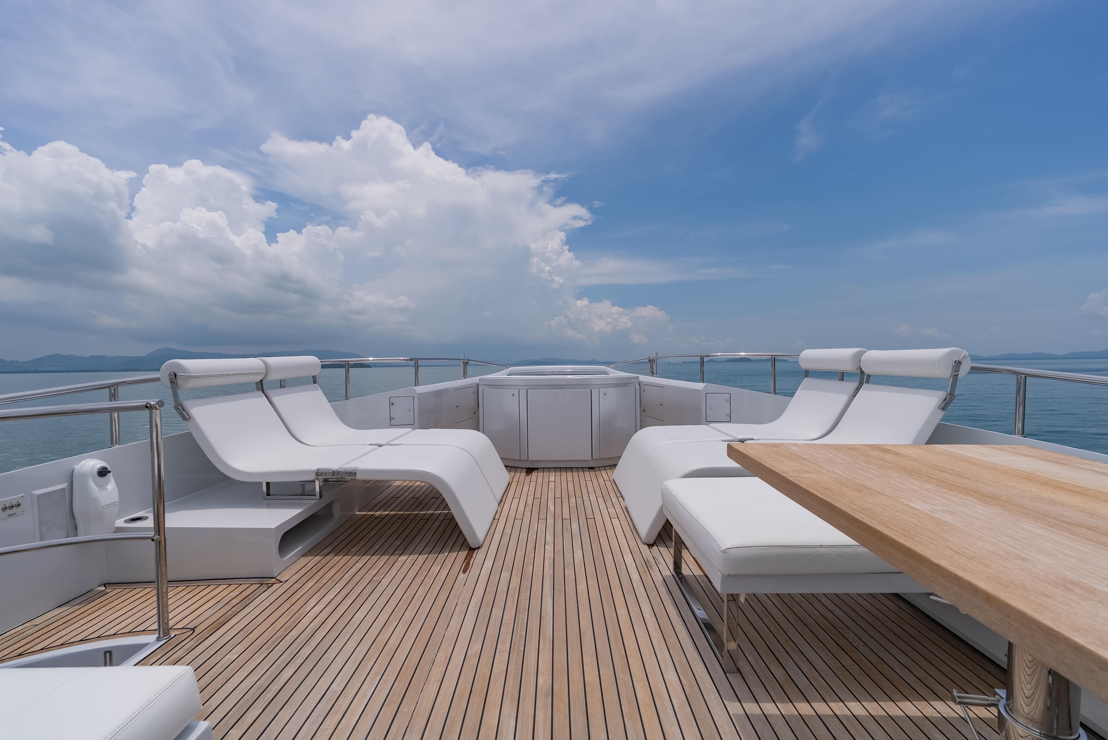 Luxurious deck of 2011 Pershing 108 yacht with white loungers and wooden flooring.