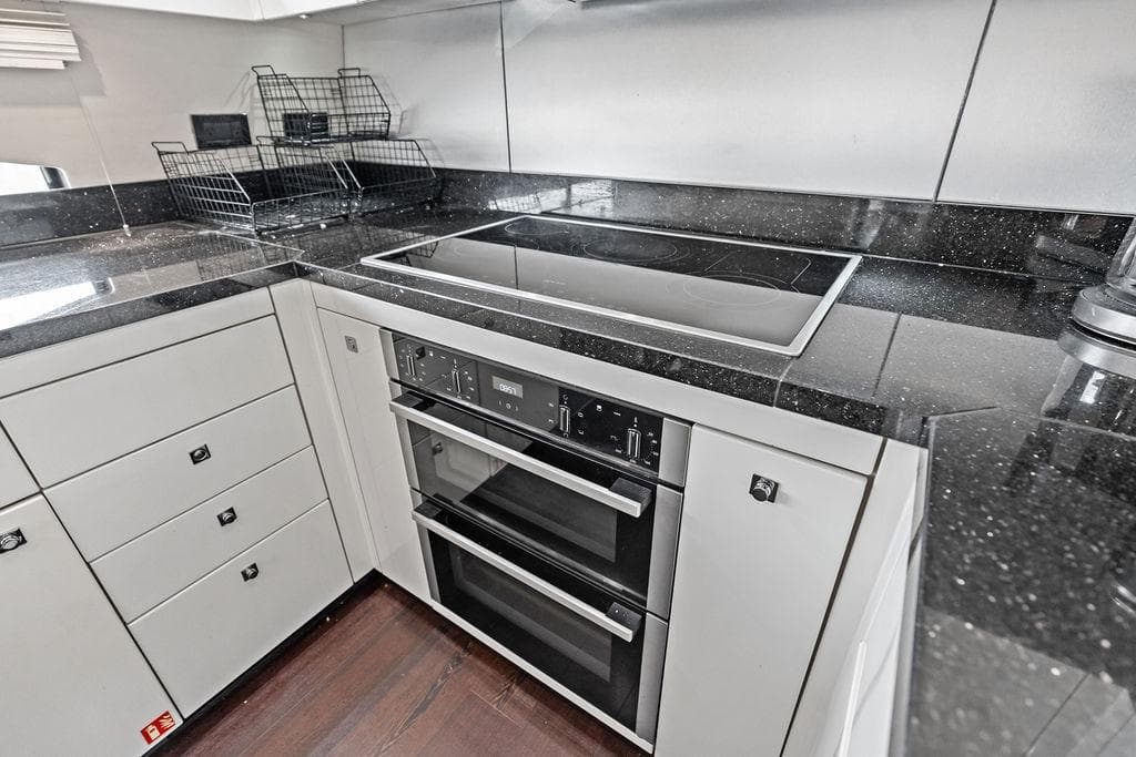 Modern kitchen in 2012 Sunseeker 88 Yacht with sleek black countertops.
