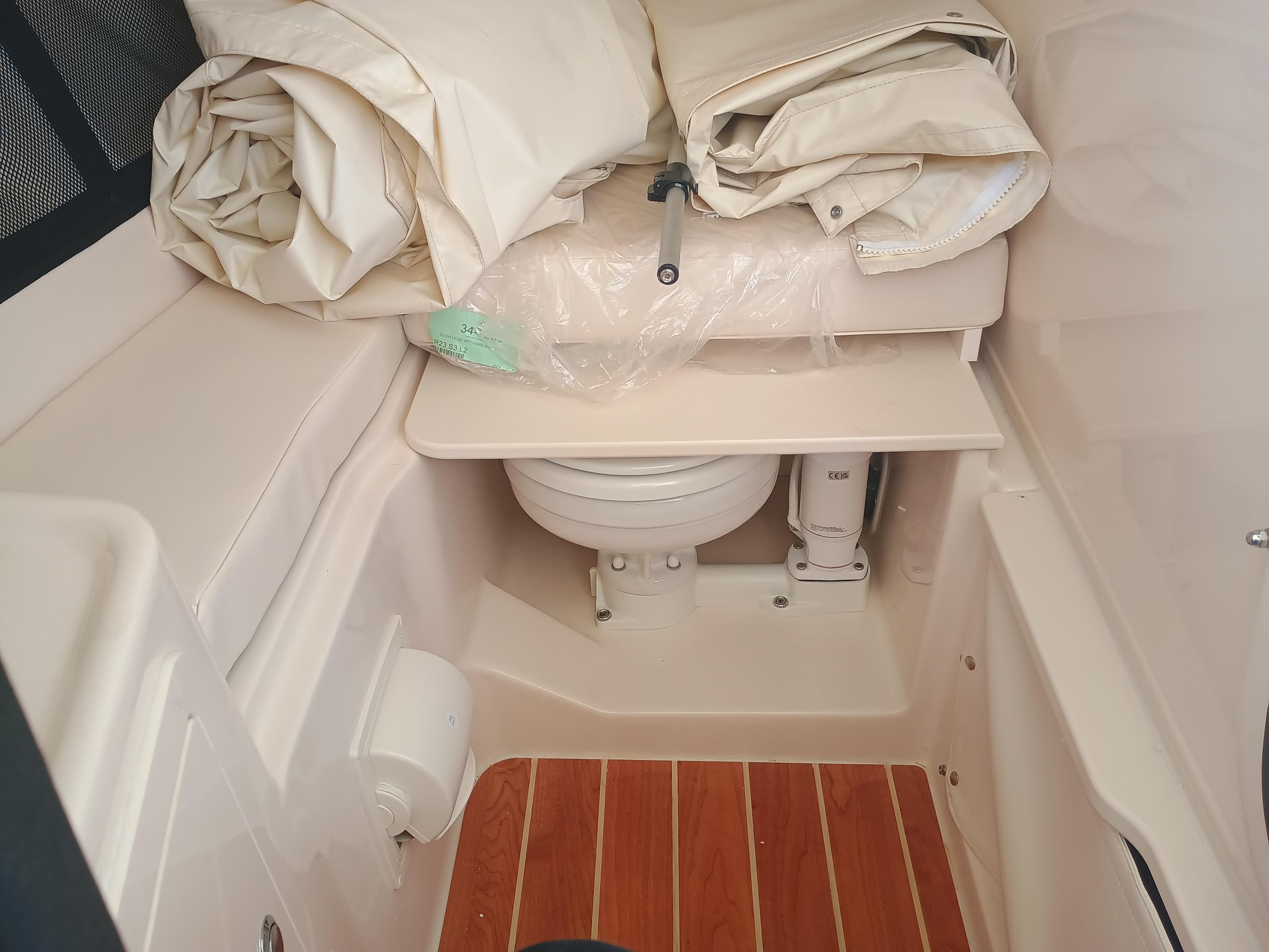 2025 Grady-White Canyon 456 boat interior with compact toilet and wooden flooring.