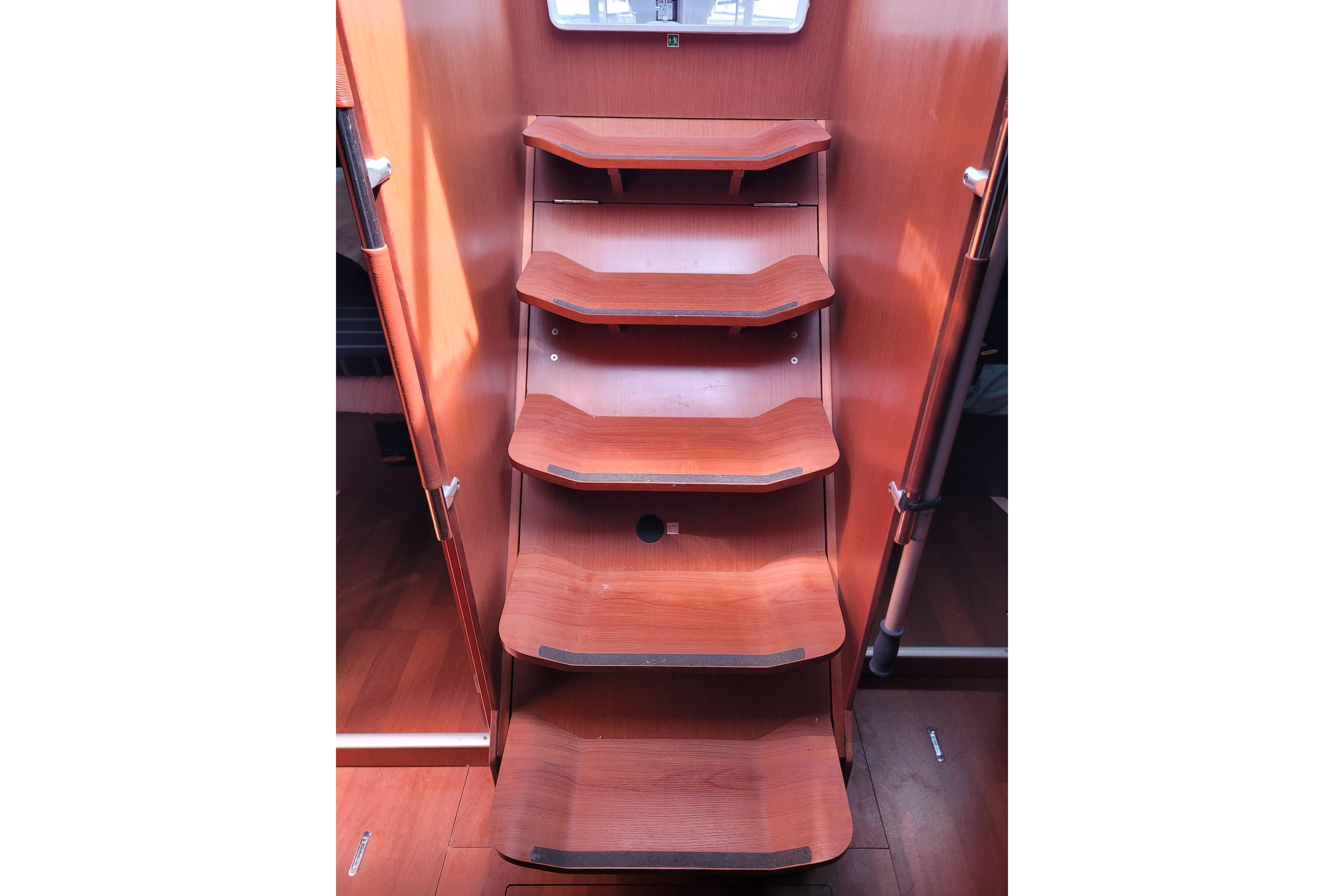 Wooden staircase inside 2015 Beneteau Oceanis 45 yacht, featuring sleek design and polished finish.