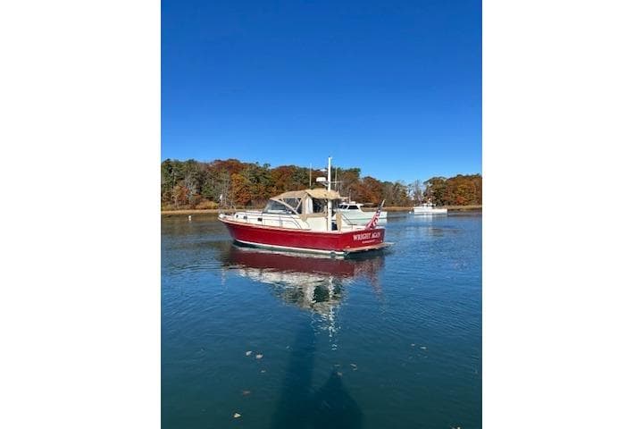 1998 Grand Banks 38 Eastbay EX boat on calm water with autumn trees in background.