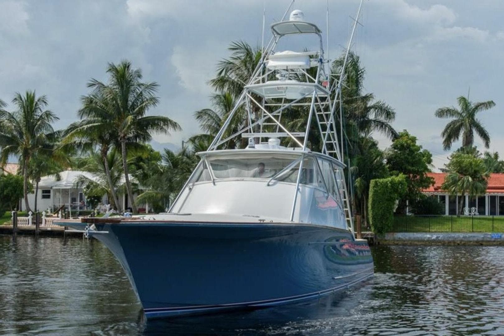 2027 Buddy Davis yacht on water, surrounded by palm trees and waterfront homes.