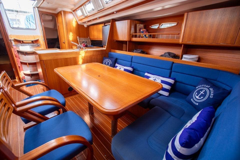 Luxurious 2005 X-Yachts 50 interior with wooden dining area and blue seating.