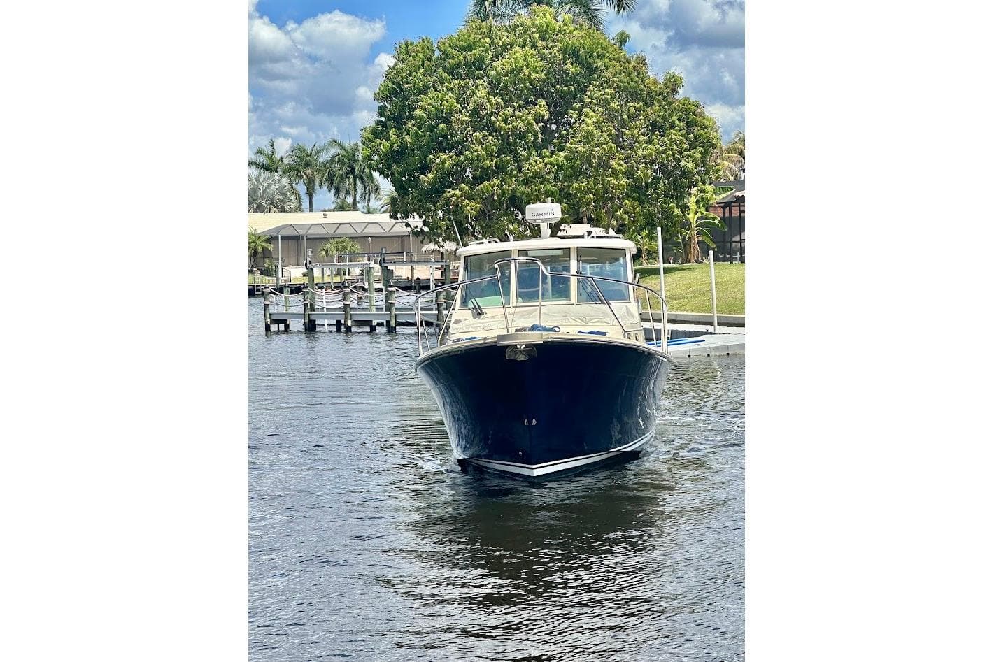 2009 Mainship Pilot 31 boat docked on a calm waterway with lush greenery.