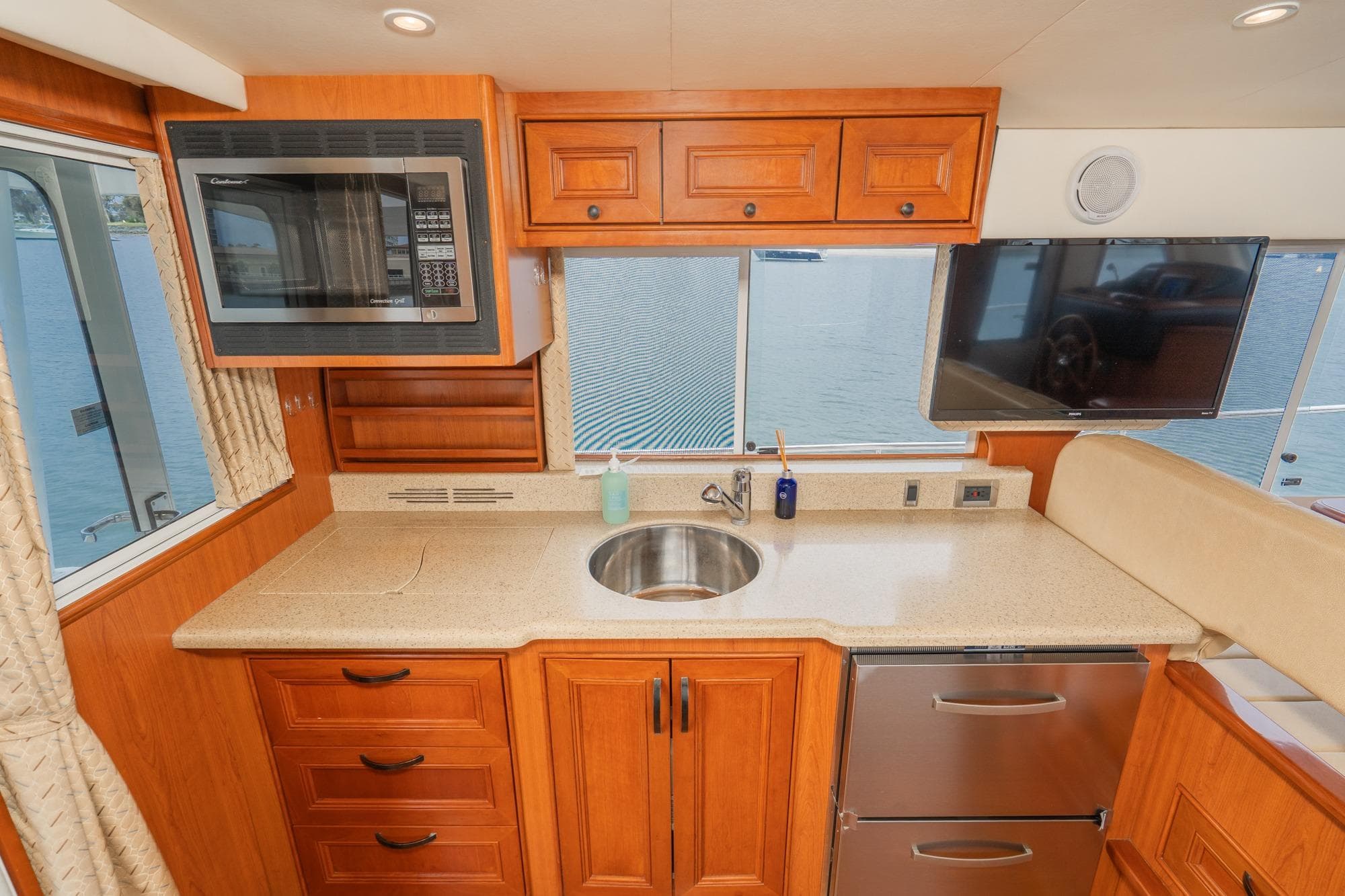 Modern kitchen in 2011 Mainship 395 Trawler with wood cabinetry, sink, and appliances.