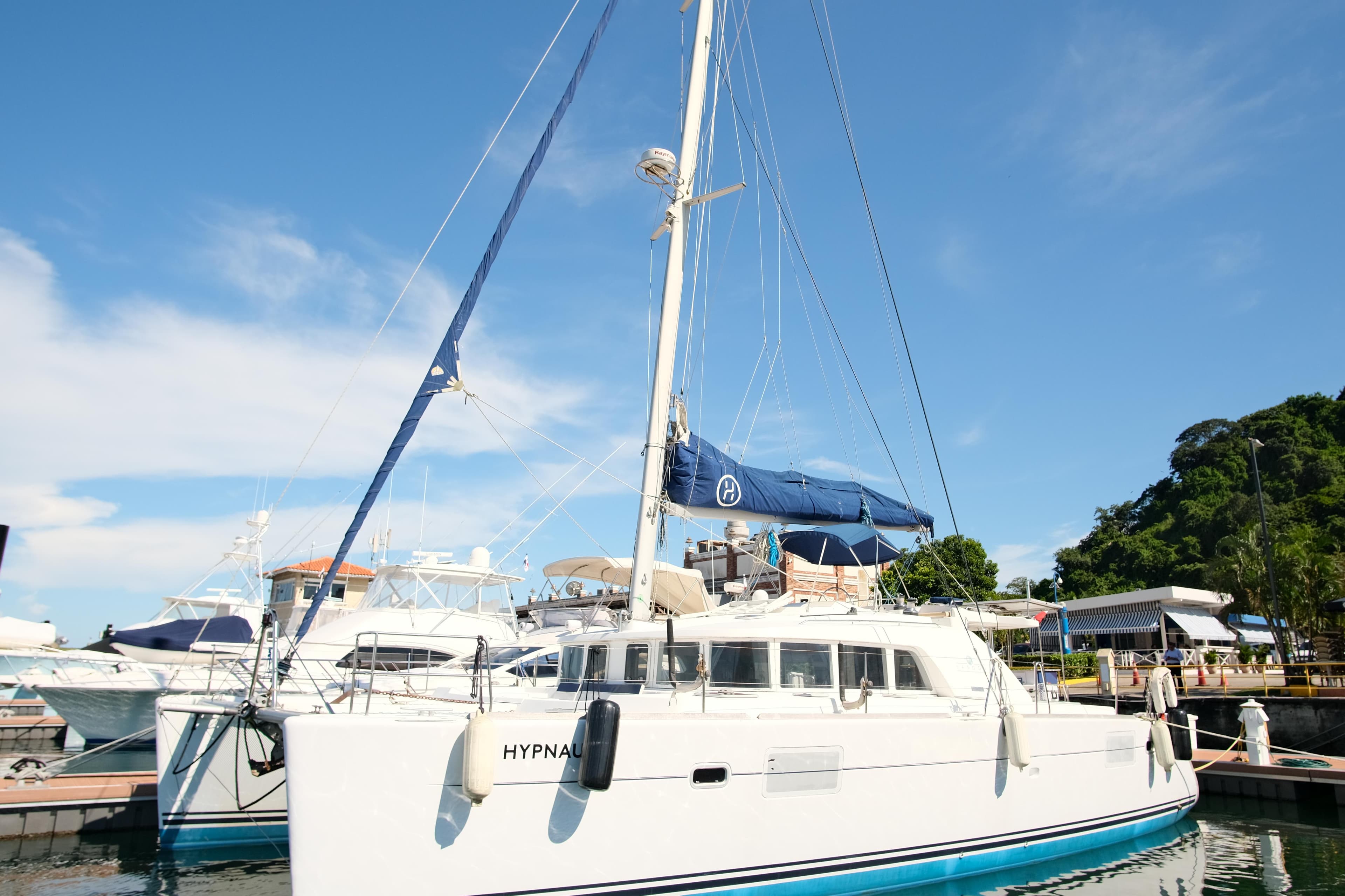 2002 Lagoon 440 catamaran docked at a marina under a clear blue sky.