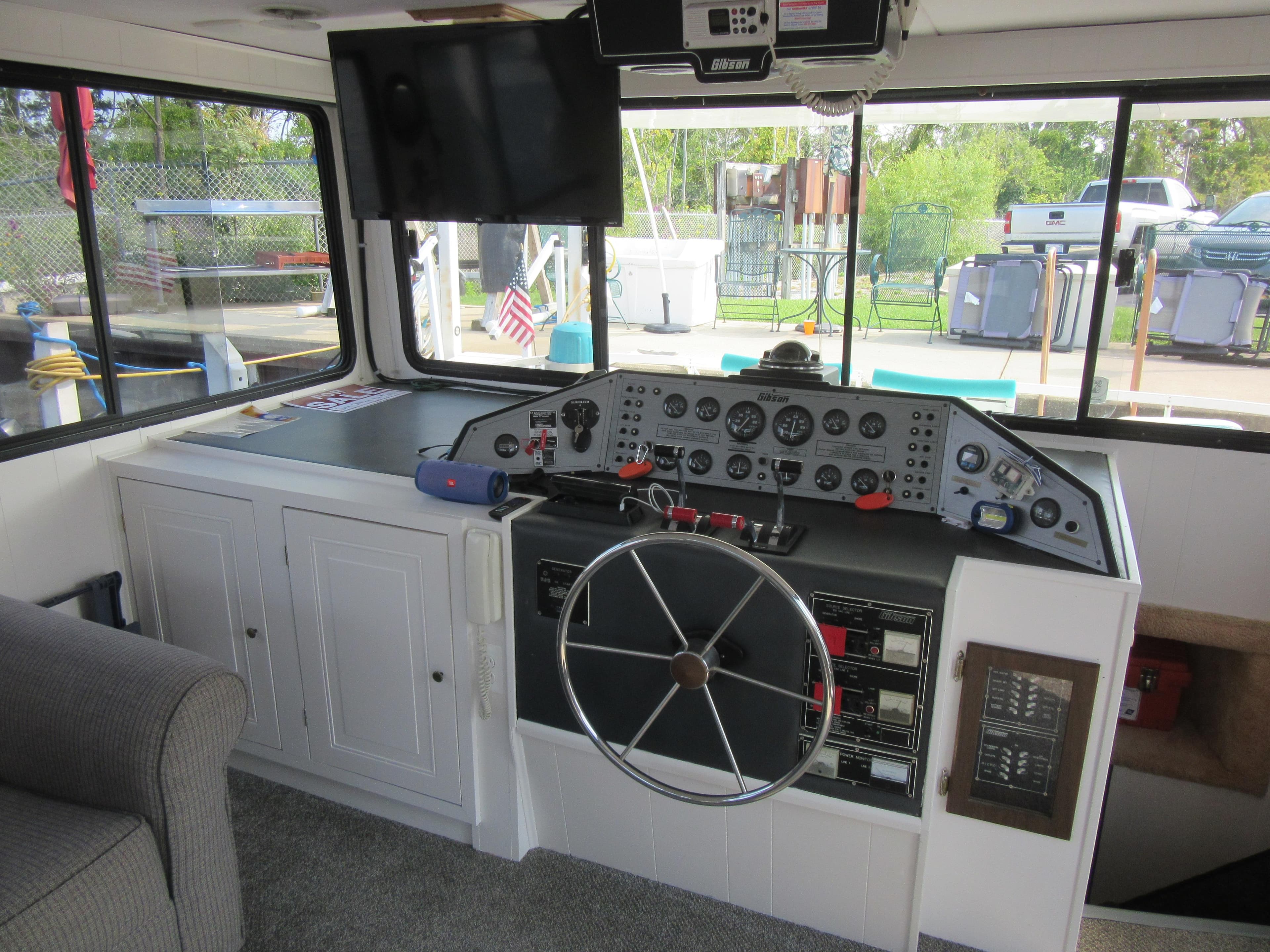 Interior helm of 1995 Gibson 44 Classic boat with steering wheel and control panel.