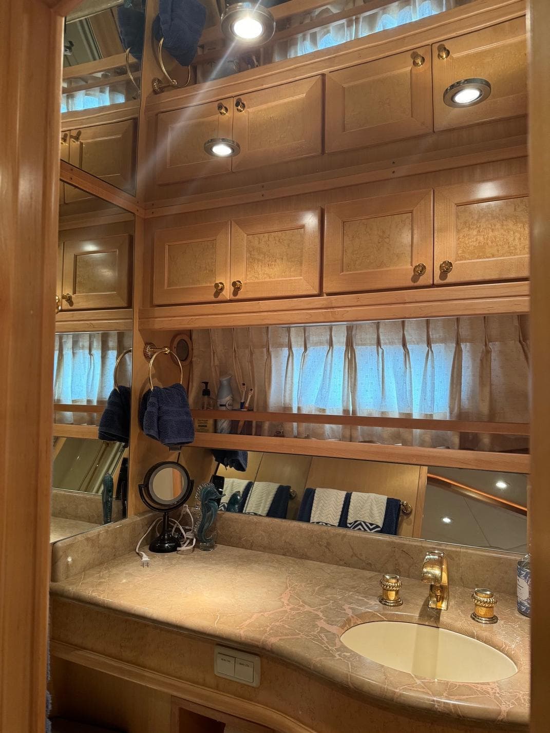 Luxurious bathroom in 2000 McKinna 57 Pilothouse yacht with wood cabinetry and marble countertop.