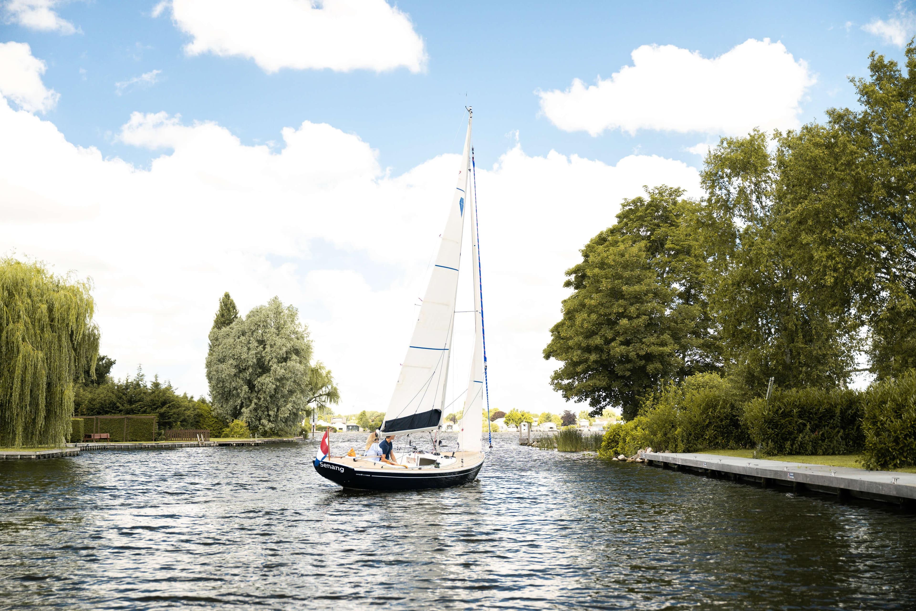 Saffier SC 6.5 Cruise 2026 sailboat navigating a scenic, tree-lined waterway.