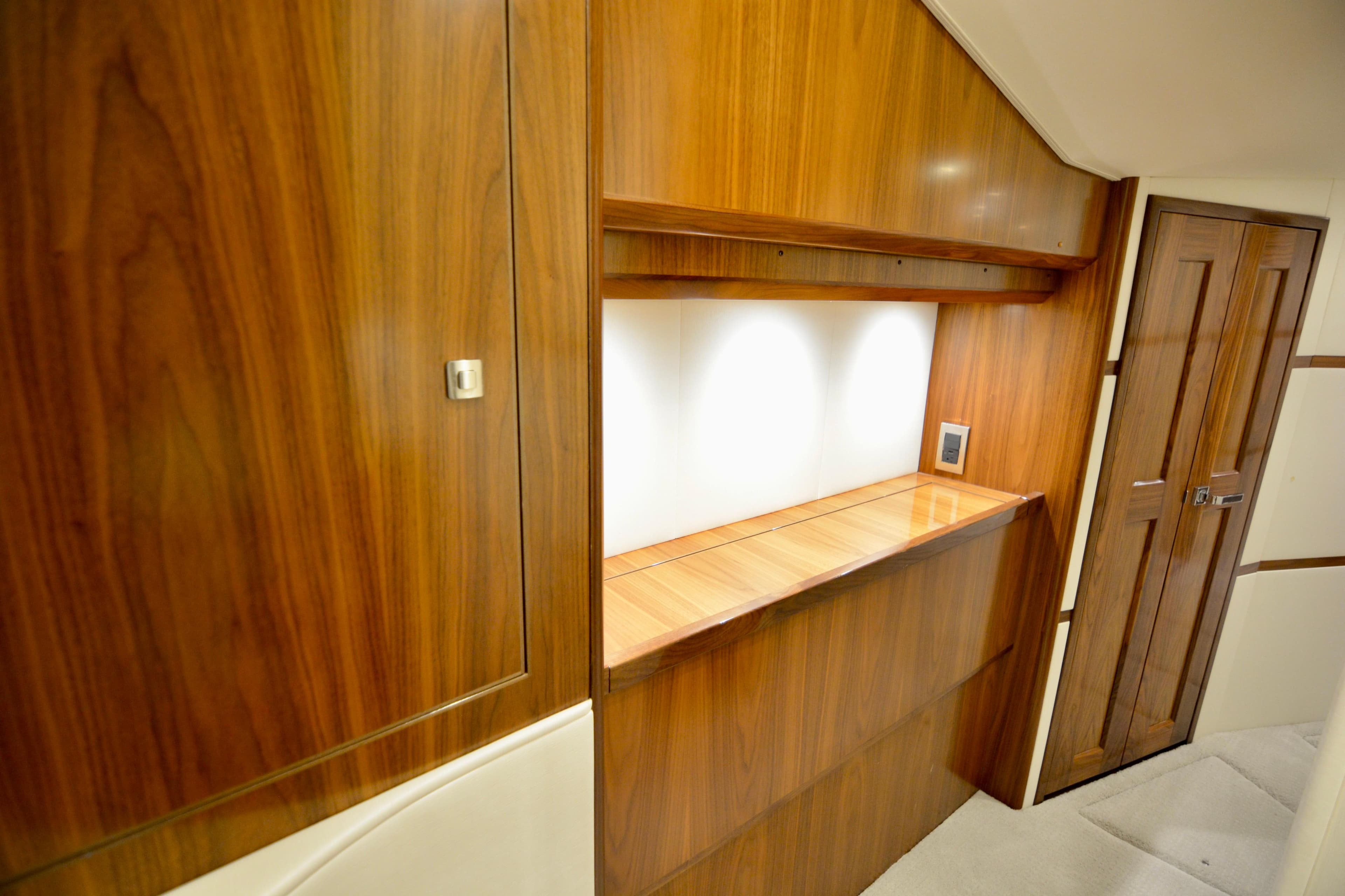 Luxurious wood interior of 2019 Viking 68 Convertible yacht, featuring elegant cabinetry and lighting.
