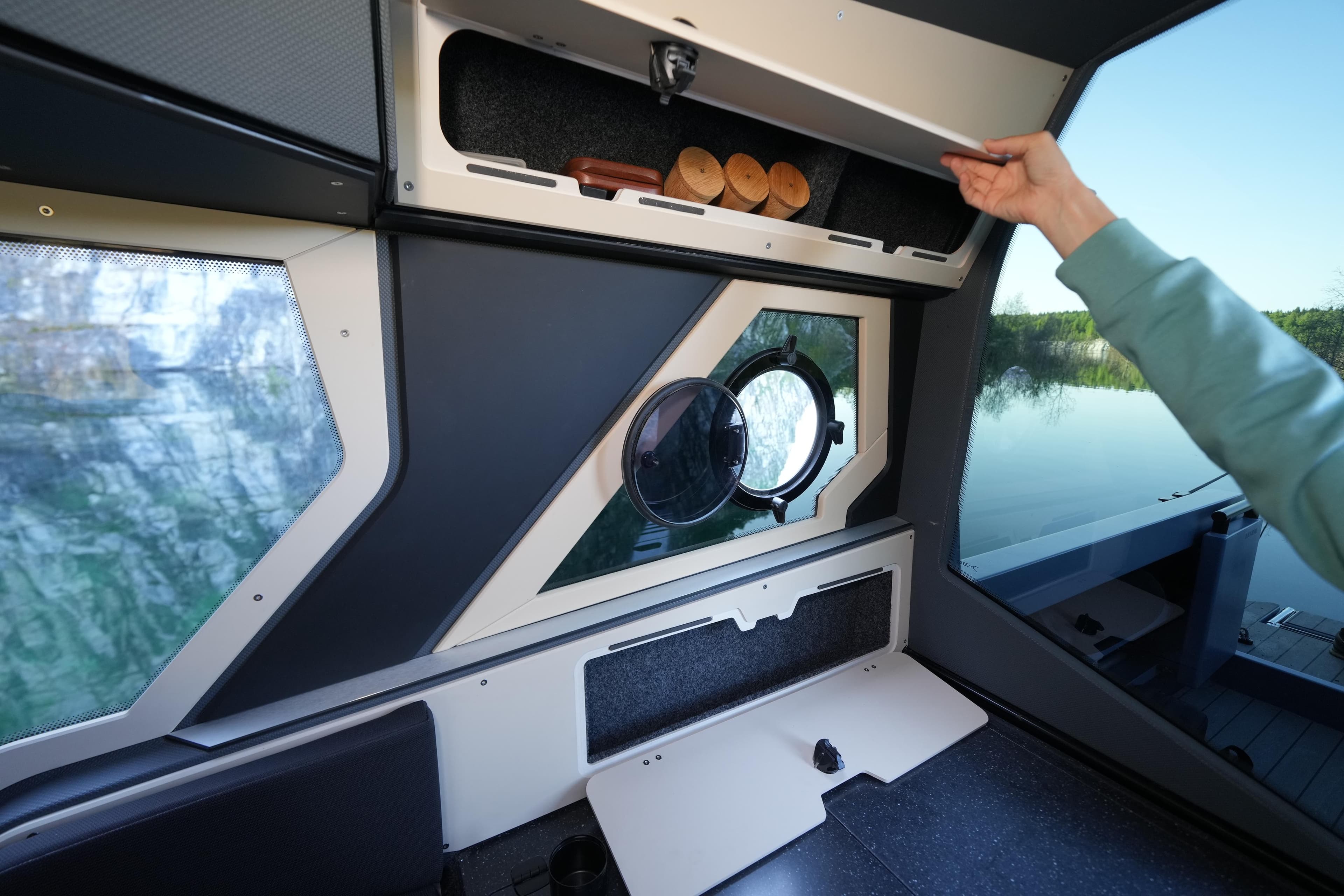 Interior of 2026 Jaktar J30 Black Vision boat with storage compartment and porthole view.