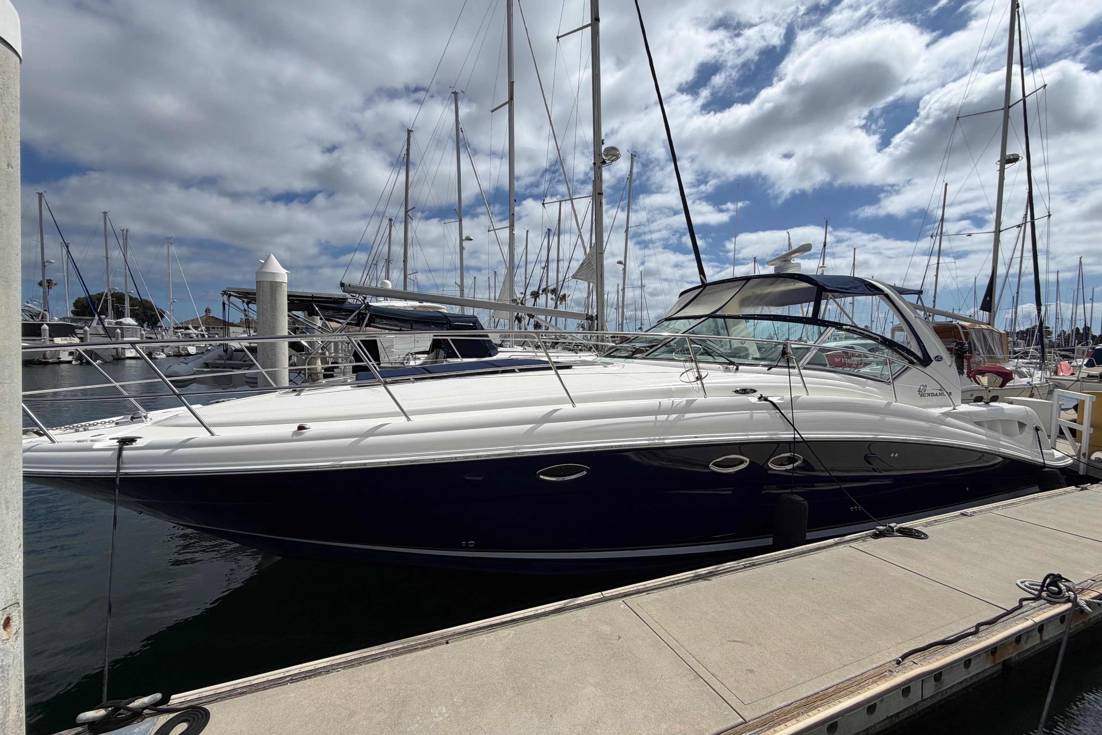 2003 Sea Ray 420 Sundancer yacht docked at a marina under a cloudy sky.