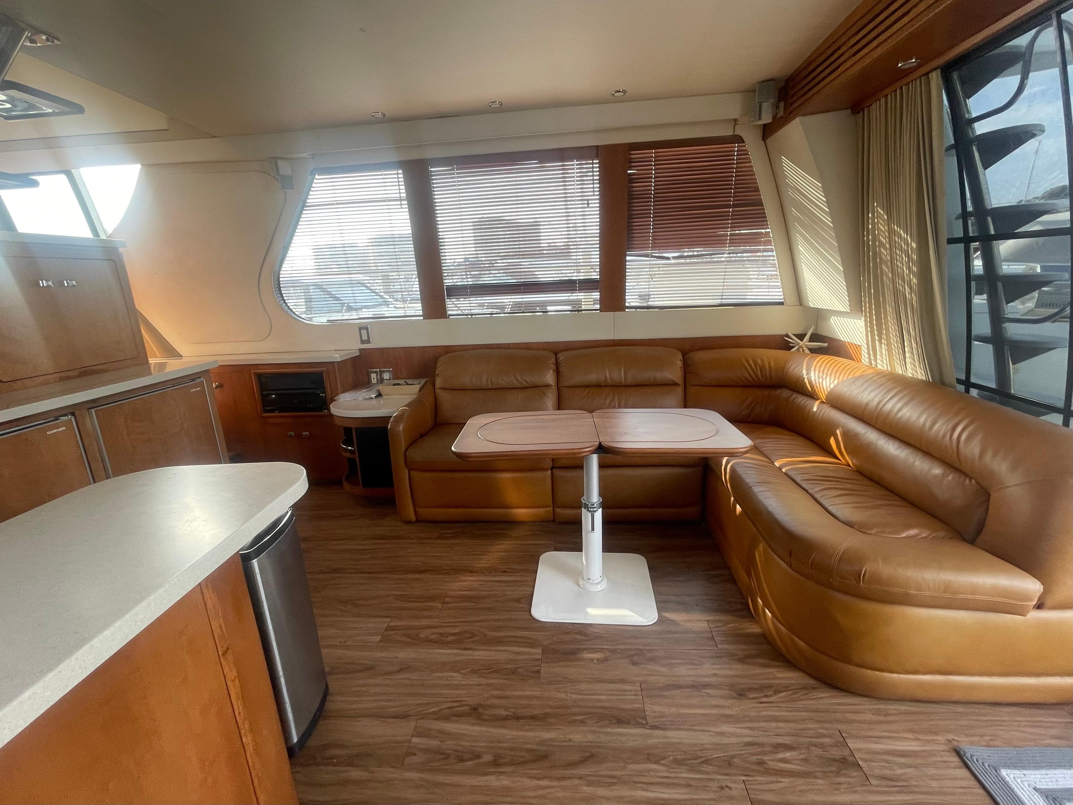 Luxurious interior of 1999 Carver Voyager yacht with leather seating and wooden flooring.