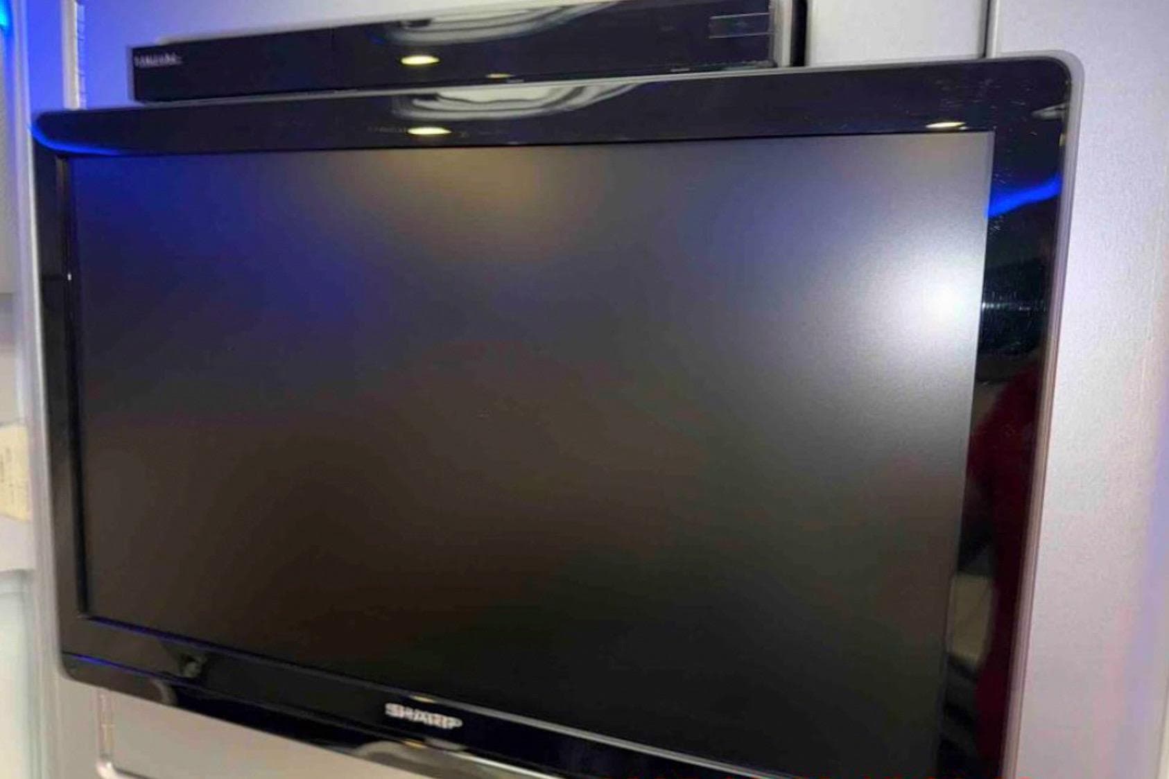Flat-screen Sharp TV mounted on a wall, with a sleek black frame.