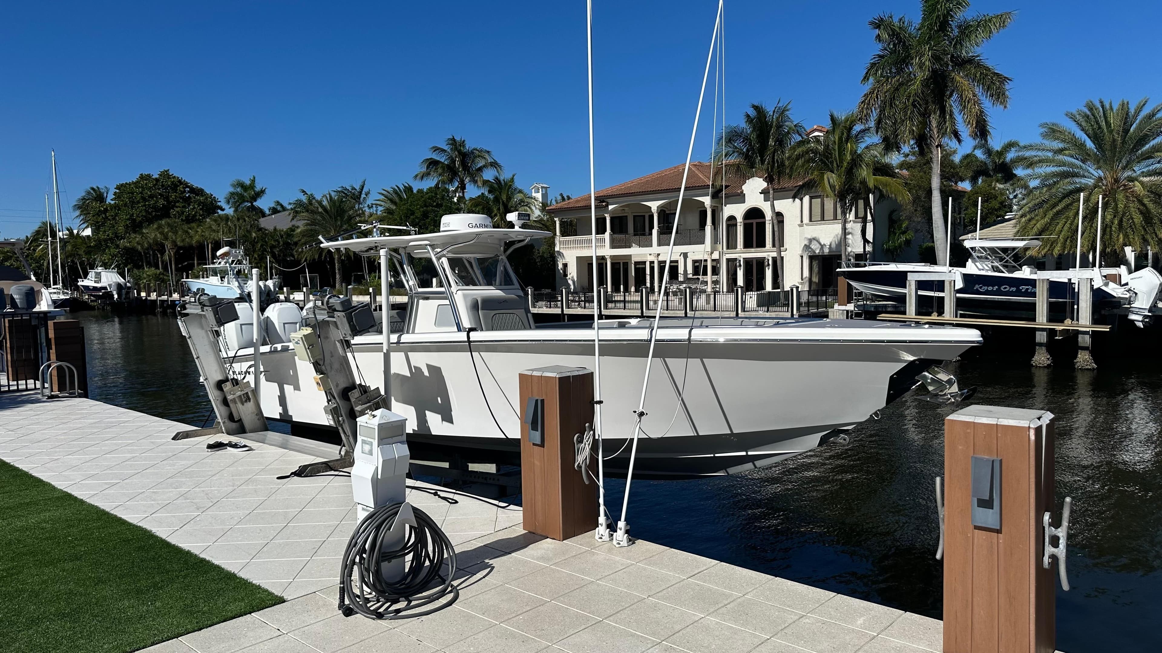 2021 Blackwater 36 SF boat docked by waterfront homes, surrounded by palm trees.