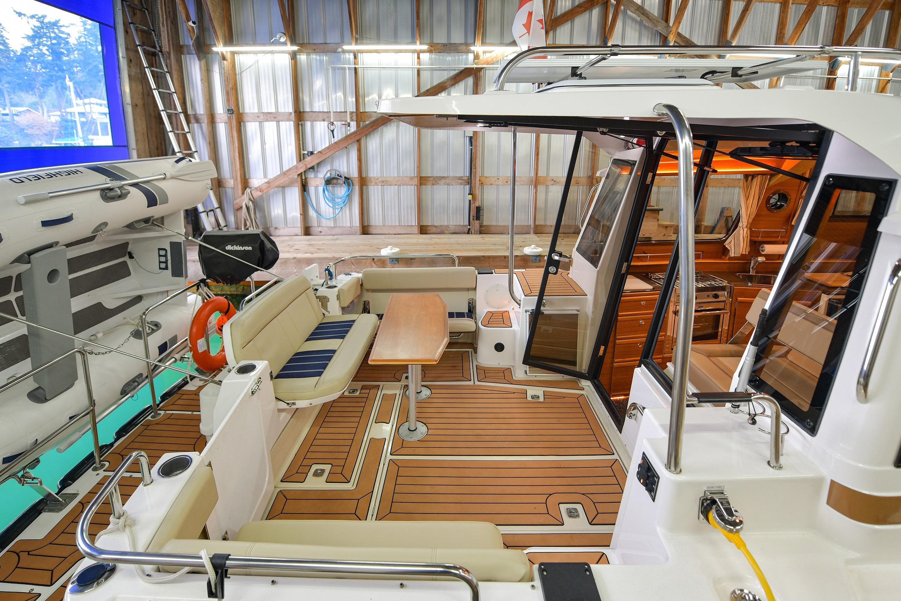 2023 Ranger Tugs R-29S boat interior with seating and wooden flooring in a boathouse.
