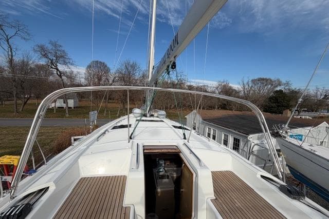 2019 Jeanneau 51 sailboat deck with open hatch, surrounded by trees and buildings.