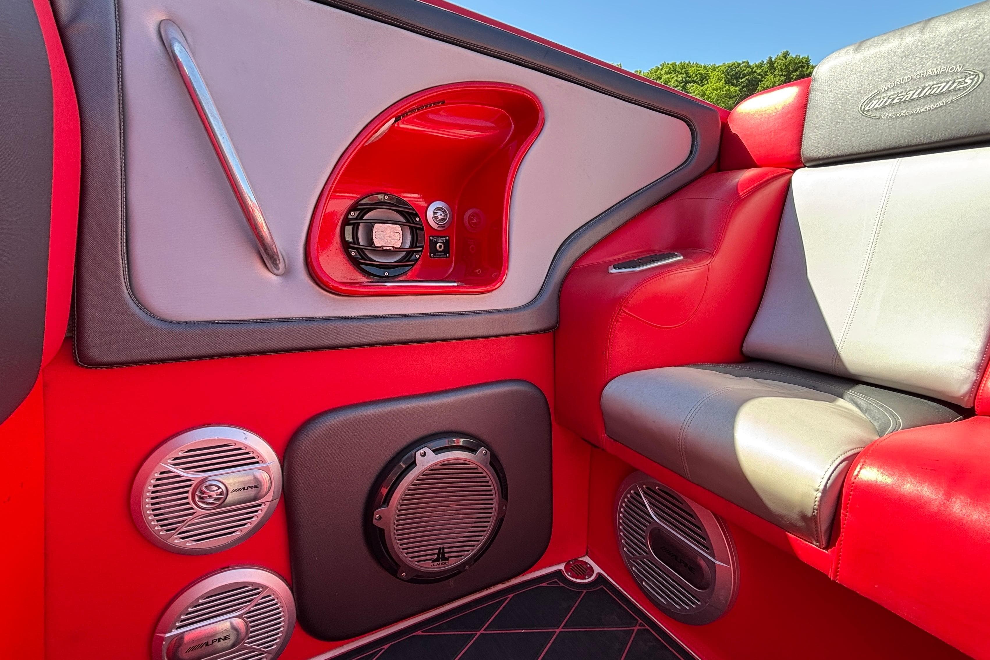 Red and gray interior of a 2004 Outerlimits 42 Legacy boat with audio speakers.