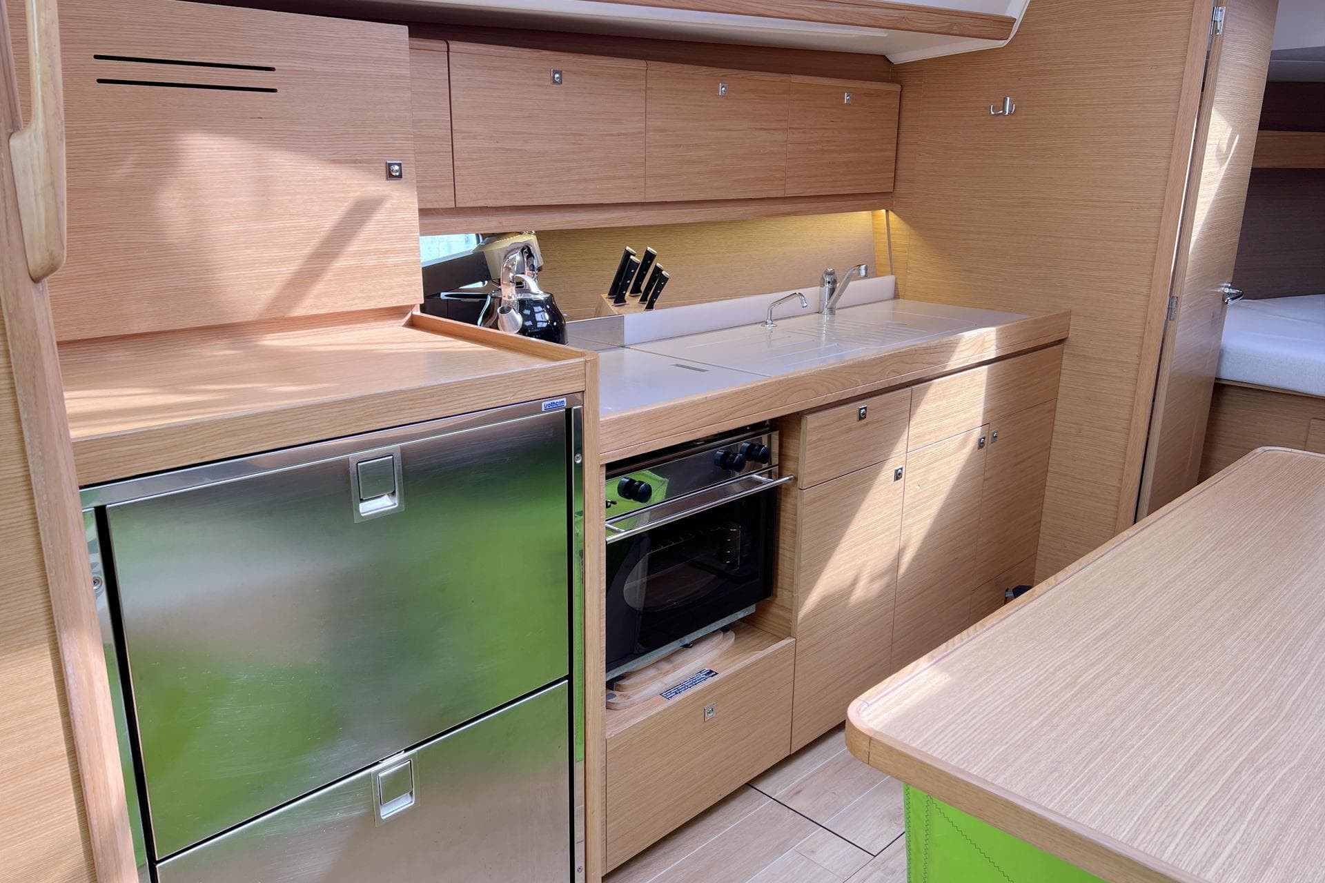 Modern kitchen interior of 2017 Dufour 382 Grand Large yacht, featuring wood cabinetry and stainless steel appliances.