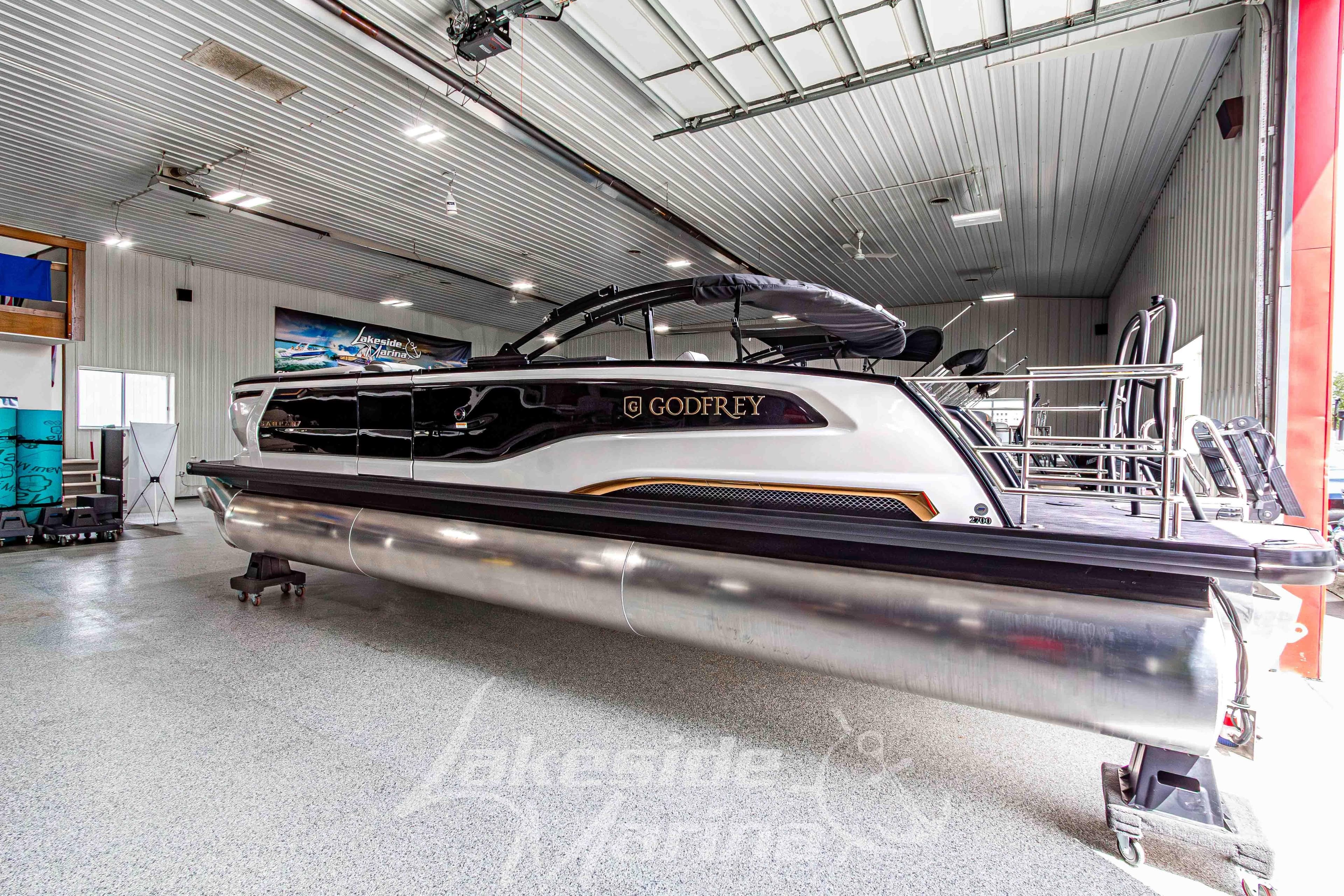 2026 Godfrey Sanpan 2700 MTF pontoon boat in a showroom, sleek design and modern features.